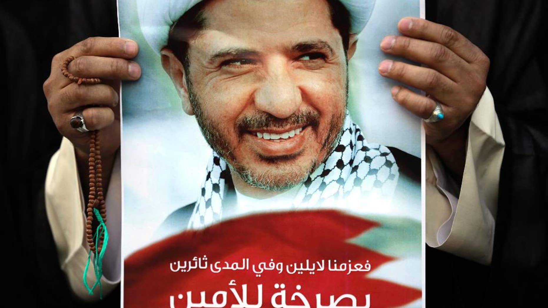 FILE - In this Feb. 25, 2015 file photo, a Bahraini anti-government protester holds up an image of jailed Shiite opposition leader Sheikh Ali Salman demanding his freedom during a protest in Daih, Bahrain. Human rights groups are sharply criticizing a Bahraini appeals court ruling that upholds a nine-year prison sentence against Salman, the country's leading Shiite opposition figure. Amnesty International and the Bahrain Institute for Rights and Democracy were among the groups condemning the Monday, Dec. 12, 2016, verdict. He is secretary-general of Al-Wefaq, Bahrain's largest Shiite political group. (AP Photo/Hasan Jamali, File)
