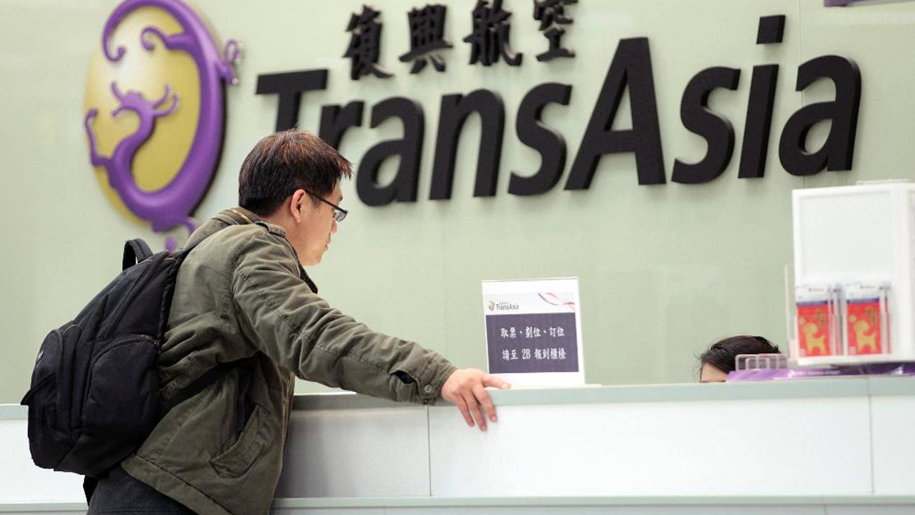 FILE- In this Saturday, Feb. 7, 2015, file photo, a passenger waits at the ticket counter of TransAsia Airways at the Songshan Airport in Taipei, Taiwan. Taiwanese airline TransAsia has announced it is shutting down following financial losses and two fatal crashes. TransAsia chairman Vincent Lin said Tuesday the airline, which served cities in China, Japan and Southeast Asia, was unable to reverse widening losses or raise additional money. (AP Photo/Wally Santana, File)