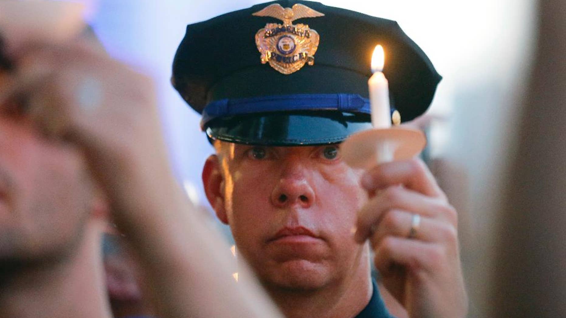 A police officers takes part in a candle light vigil at City Hall, Monday, July 11, 2016, in Dallas. Five police officers were killed and several injured during a shooting in downtown Dallas last Thursday night. (AP Photo/Tony Gutierrez)