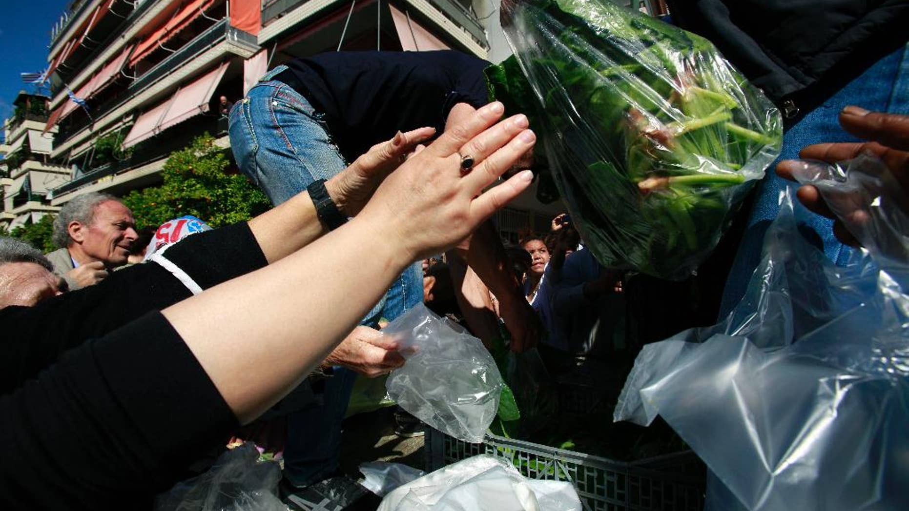 Greek farmers' market vendors distribute free produce as part of a protest in Athens, Wednesday, April 30, 2014, after their trading association launched an indefinite strike Monday. The market vendors are the latest professional group in Greece to protest a sweeping liberalization drive demanded by rescue creditors. (AP Photo/Dimitri Messinis)