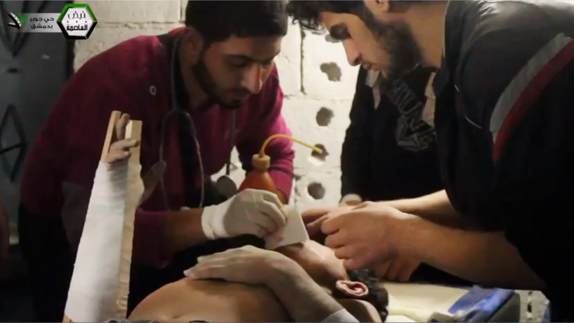 In this image taken from Thursday, Oct. 24, 2013 video obtained from the Shaam News Network, which has been authenticated based on its contents and other AP reporting, two men treat a civilian young man rescued from the wreckage of a building after it was struck by government forces in the suburb of Jobar, Damscus, Syria. The Syrian conflict, which began as a largely peaceful uprising against Assad in March 2011, has triggered a humanitarian crisis on a massive scale, killing more than 100,000 people, driving nearly 7 million more from their homes and devastating the nation's cities and towns. (AP Photo/Shaam News Network via AP Video)