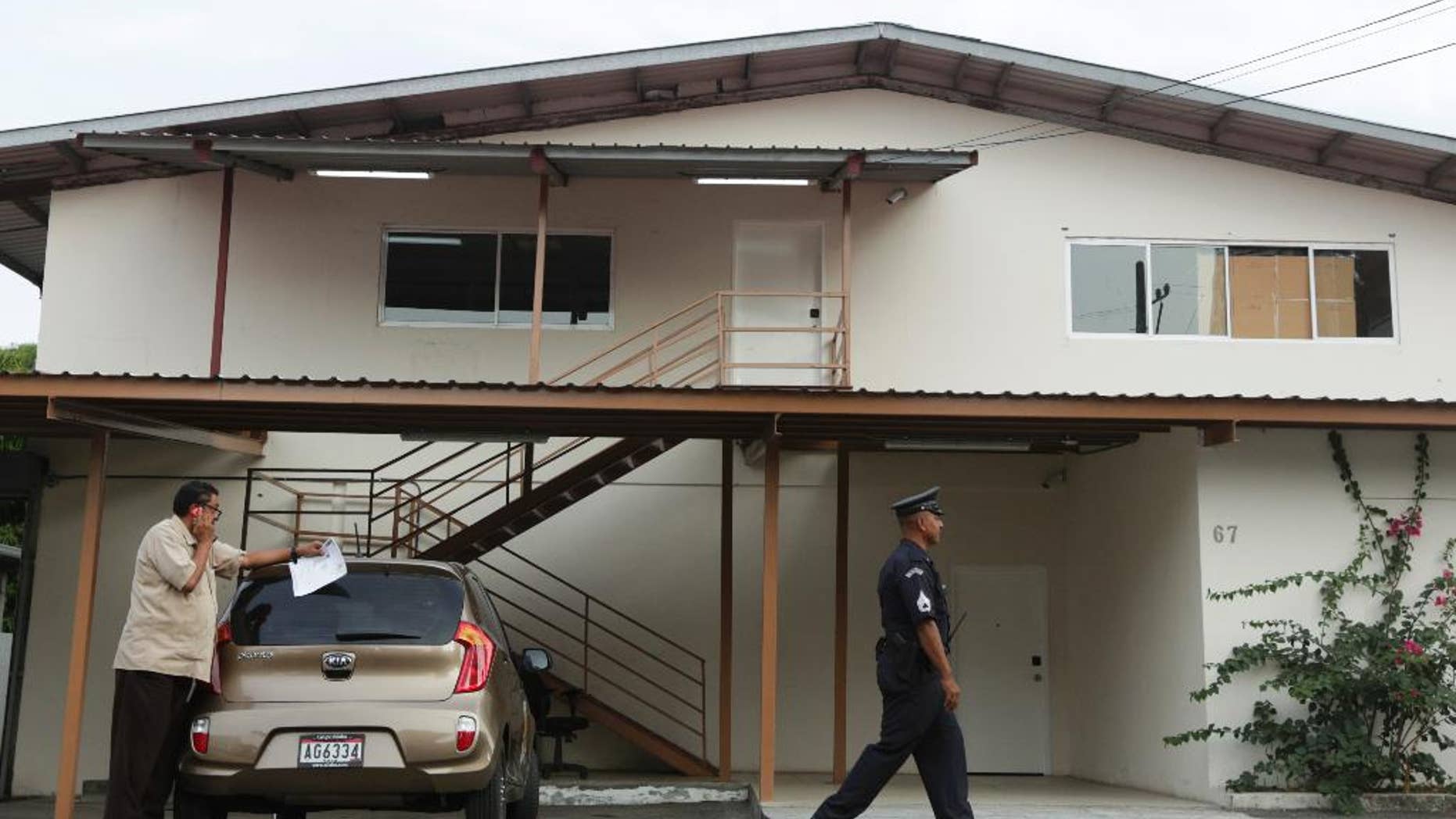 A Panamanian police officer and private security guard stand outside a warehouse used by the Mossack-Fonseca law firm, that was raided by prosecutors, in Panama City, Friday, April 22, 2016. A week before prosecutors had wrapped up their search of the Mossack Fonseca law firm looking for evidence of any illegal activity in the company at the center of a document leak that revealed details of offshore financial accounts.(AP Photo/Arnulfo Franco)