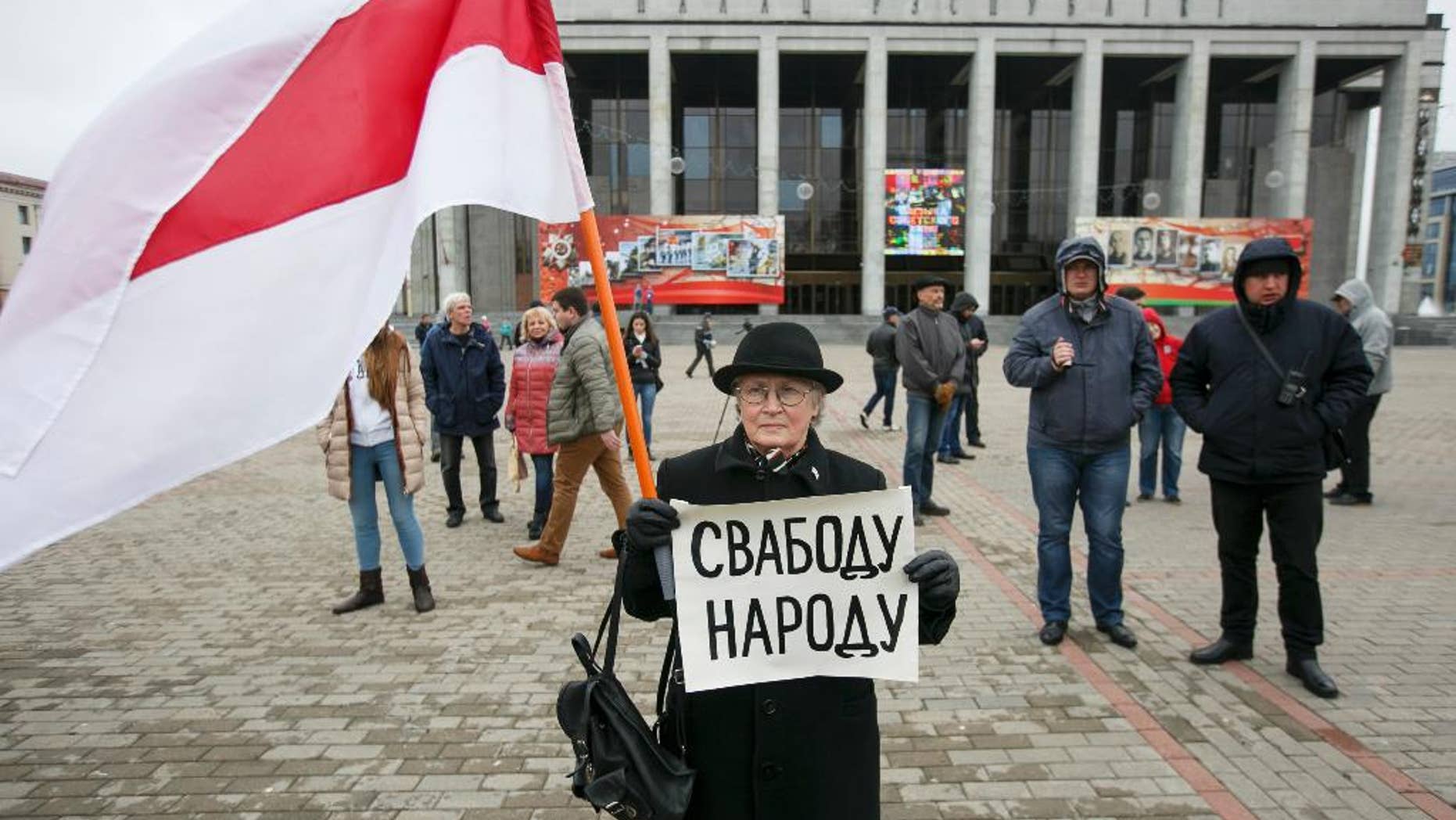 A protester holds a poster reading 'Freedom for the people' and an old Belarus flag, a symbol of protest, during an opposition rally in Minsk, Belarus, Monday, May 1, 2017. The protesters marched through central Minsk calling for the government to step down and for free elections to be held. (AP Photo)
