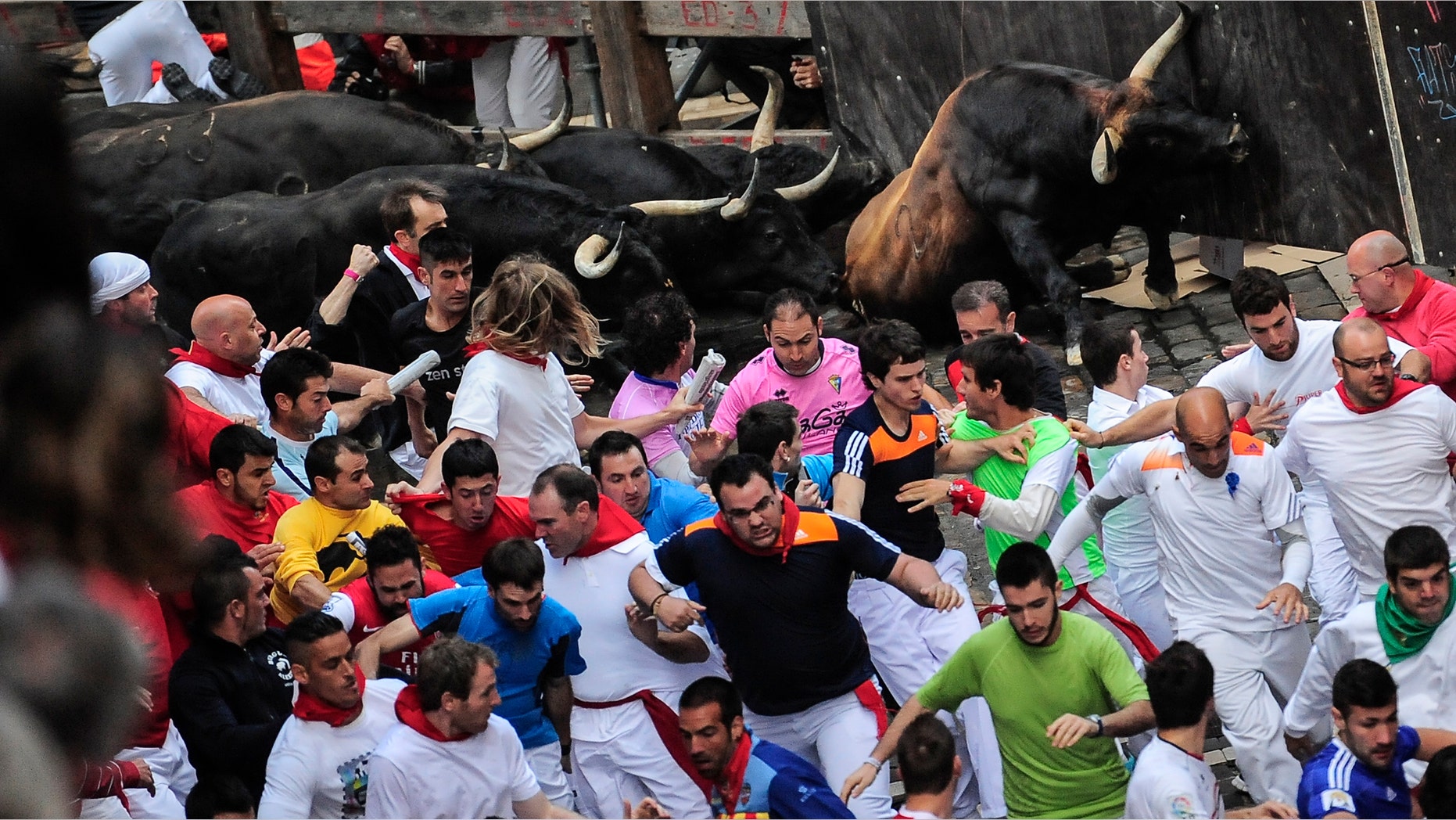 Revelers run ahead of ''Jandilla'' fighting bulls on Estafeta corner on the way to the bull ring, during the running of the bulls, at the San Fermin festival, in Pamplona, Spain, Friday, July 11, 2014. Revelers from around the world arrive to Pamplona every year to take part in some of the eight days of the running of the bulls. (AP Photo/Alvaro Barrientos)