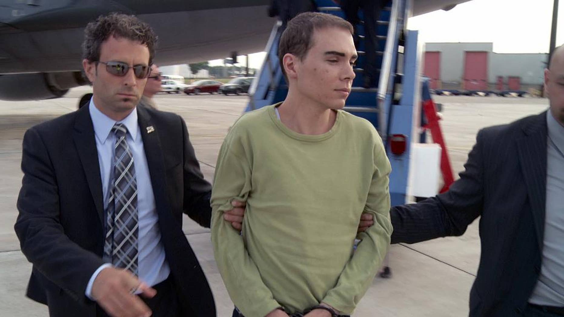 FILE - In this June 18, 2012 file photo provided by Montreal Police, Luka Rocco Magnotta is taken by police from a Canadian military plane to a waiting van in Mirabel, Quebec. Magnotta dropped his appeal Wednesday, Feb. 18, 2015 of a life sentence for killing and dismembering his Chinese lover and mailing his body parts to schools and political parties. Magnotta, 32, was sentenced to life in prison last December in the slaying and dismemberment of Jun Lin, a 33-year-old Chinese engineering student who had been living in Canada since 2011. (AP Photo/Montreal Police)