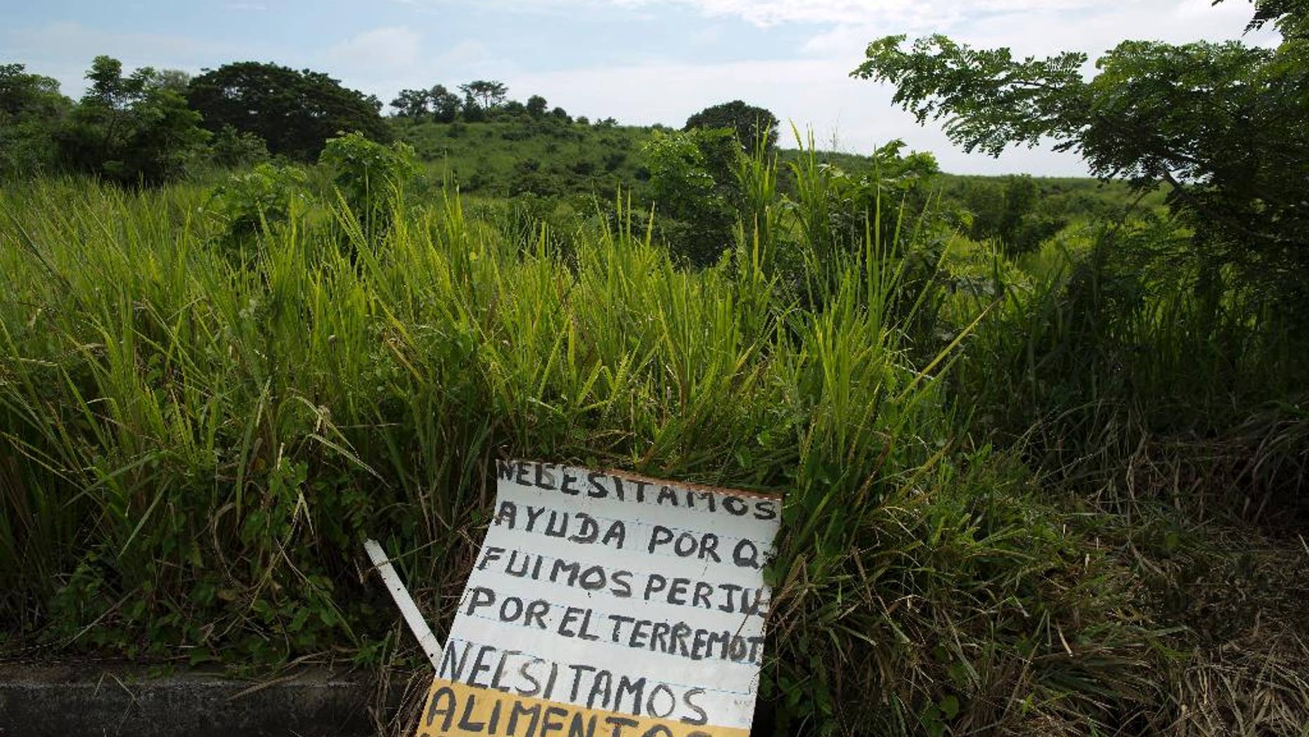This April 25, 2016 photo shows a sign that reads in Spanish; "We need help because we were affected by the earthquake, we need food and medicine," on the side of a highway outside Pedernales, Ecuador. More than a dozen roads were closed due to damage from th April 16, 7.8-magnitude earthquake, making it harder for rescuers to reach where they were needed most. (AP Photo/Rodrigo Abd)