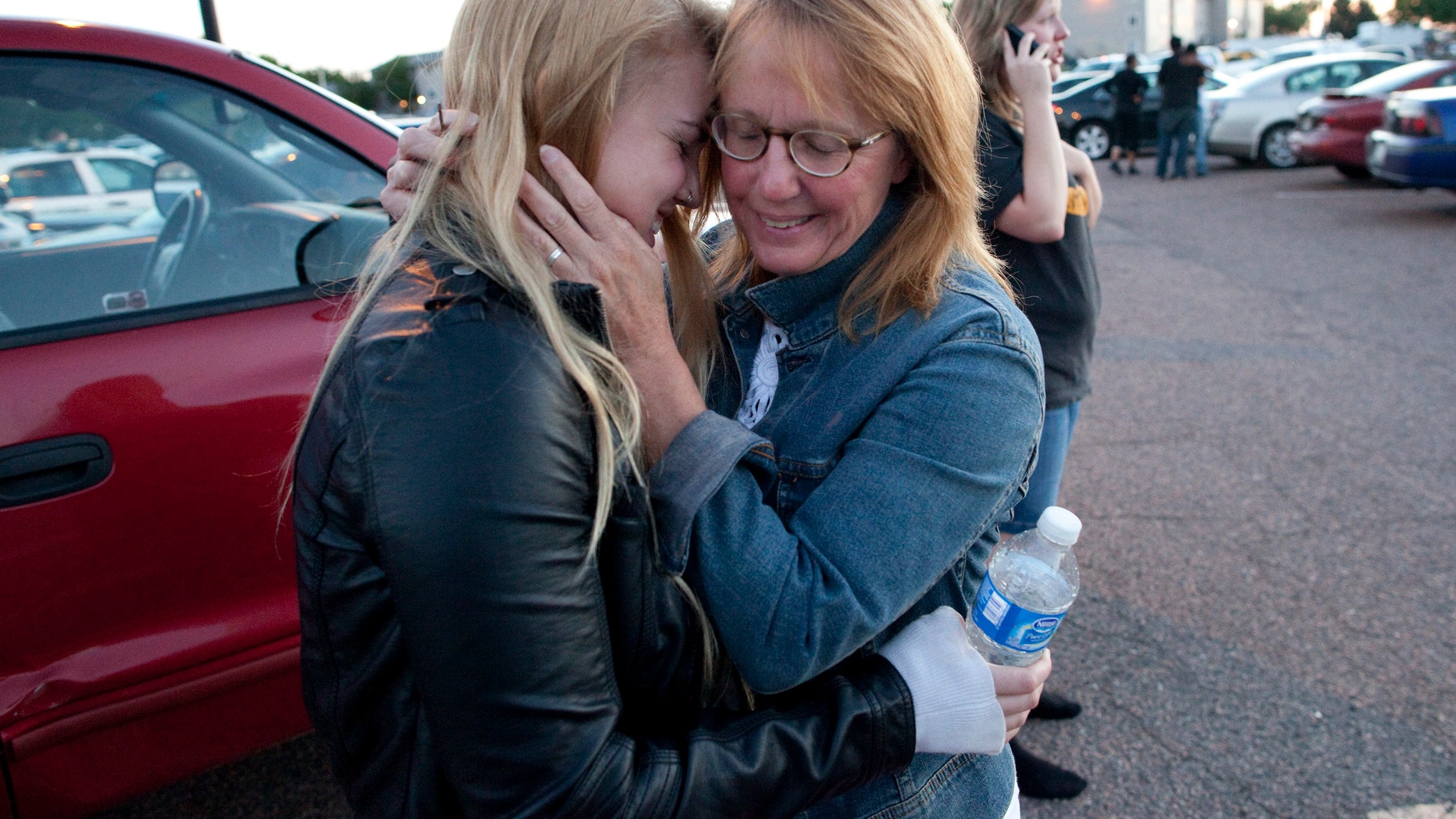 July 20, 2012: Emma Goos, 19, hugs her mother, Judy Goos, outside Gateway High School where witnesses were brought for questioning Friday, in Aurora, Colo. Emma was in the third row of the theater of the new Batman movie when the shooter entered. She helped apply pressure to a man's head who was injured.