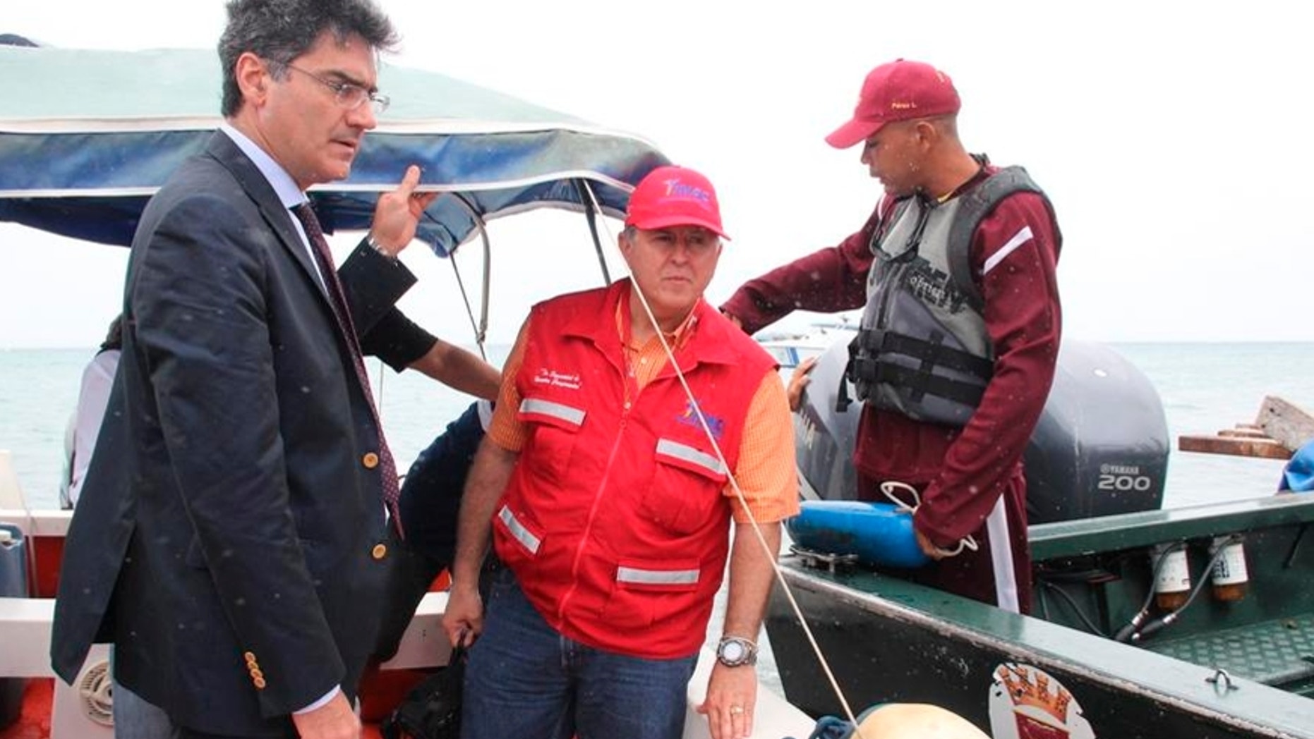 In this photo provided by Venezuela's Ministry of the Interior and Justice Press Office, Italy's ambassador to Venezuela Paolo Serpi, left, speaks with rescue team members prior to their continued search for a missing plane off Los Roques, Venezuela, Monday, Jan. 7, 2013. The search for a missing plane carrying Italian fashion executive Vittorio Missoni and five other people has entered its fourth straight day on Monday with no signs of the aircraft. The small, twin-engine plane was reported missing hours after taking off Friday from Los Roques, a string of islands and islets popular among tourists for their white beaches and coral reefs. (AP Photo/Venezuela Ministry Interior and Justice Office Press)