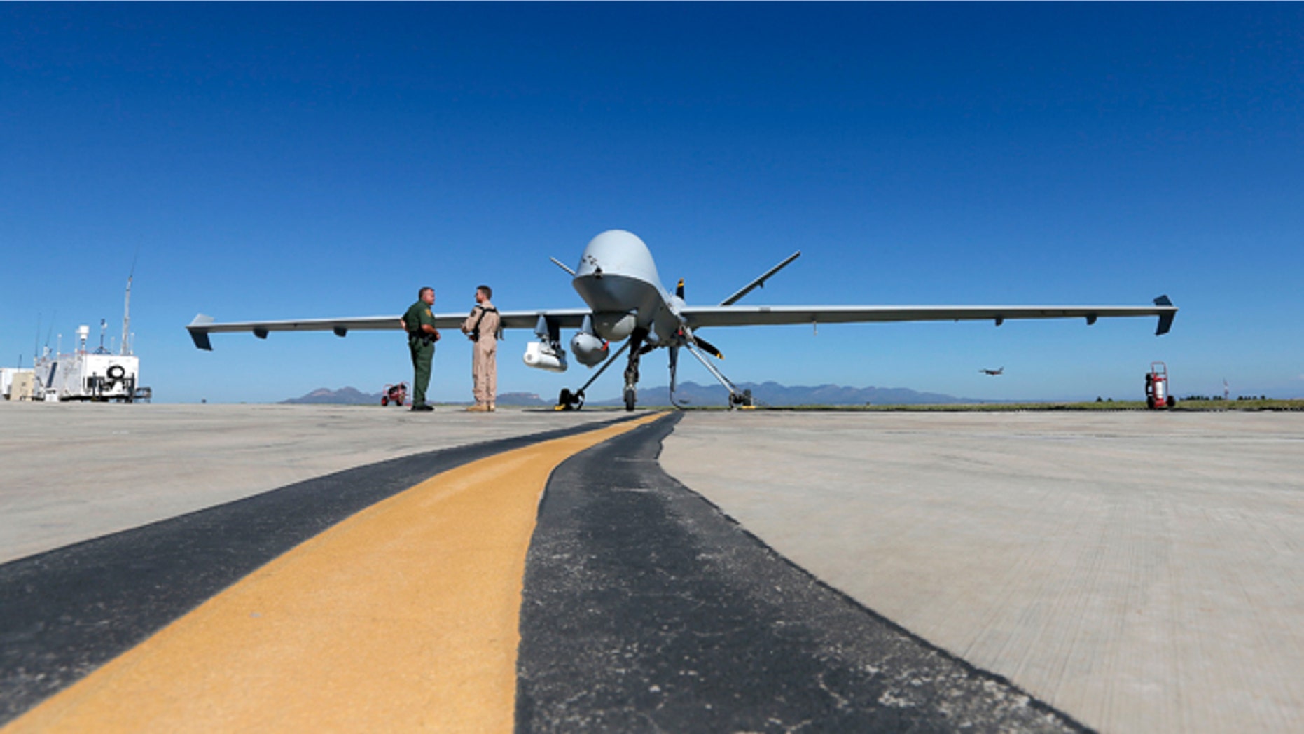 Lothar Eckardt, right, executive director of National Air Security Operations at U.S. Customs and Border Protection, speaks with a Customs and Border Patrol agent prior to a drone aircraft flight, Wednesday, Sept 24, 2014 at Ft. Huachuca in Sierra Vista, Ariz. The U.S. government now patrols nearly half the Mexican border by drones alone in a largely unheralded shift to control desolate stretches where there are no agents, camera towers, ground sensors or fences, and it plans to expand the strategy to the Canadian border. It represents a significant departure from a decades-old approach that emphasizes boots on the ground and fences. (AP Photo/Matt York)