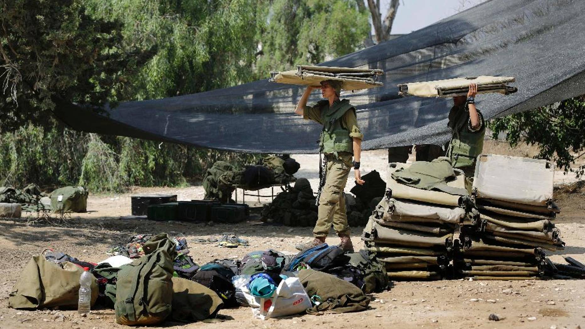 Israeli soldiers carry a bunk beds near the Israel Gaza border, Israel, Monday, July 7, 2014. The Islamic militant group Hamas that rules Gaza vowed revenge on Israel for the death of several of its members killed in an airstrike early Monday morning in the deadliest exchange of fire since the latest round of attacks began weeks ago. (AP Photo/Tsafrir Abayov)