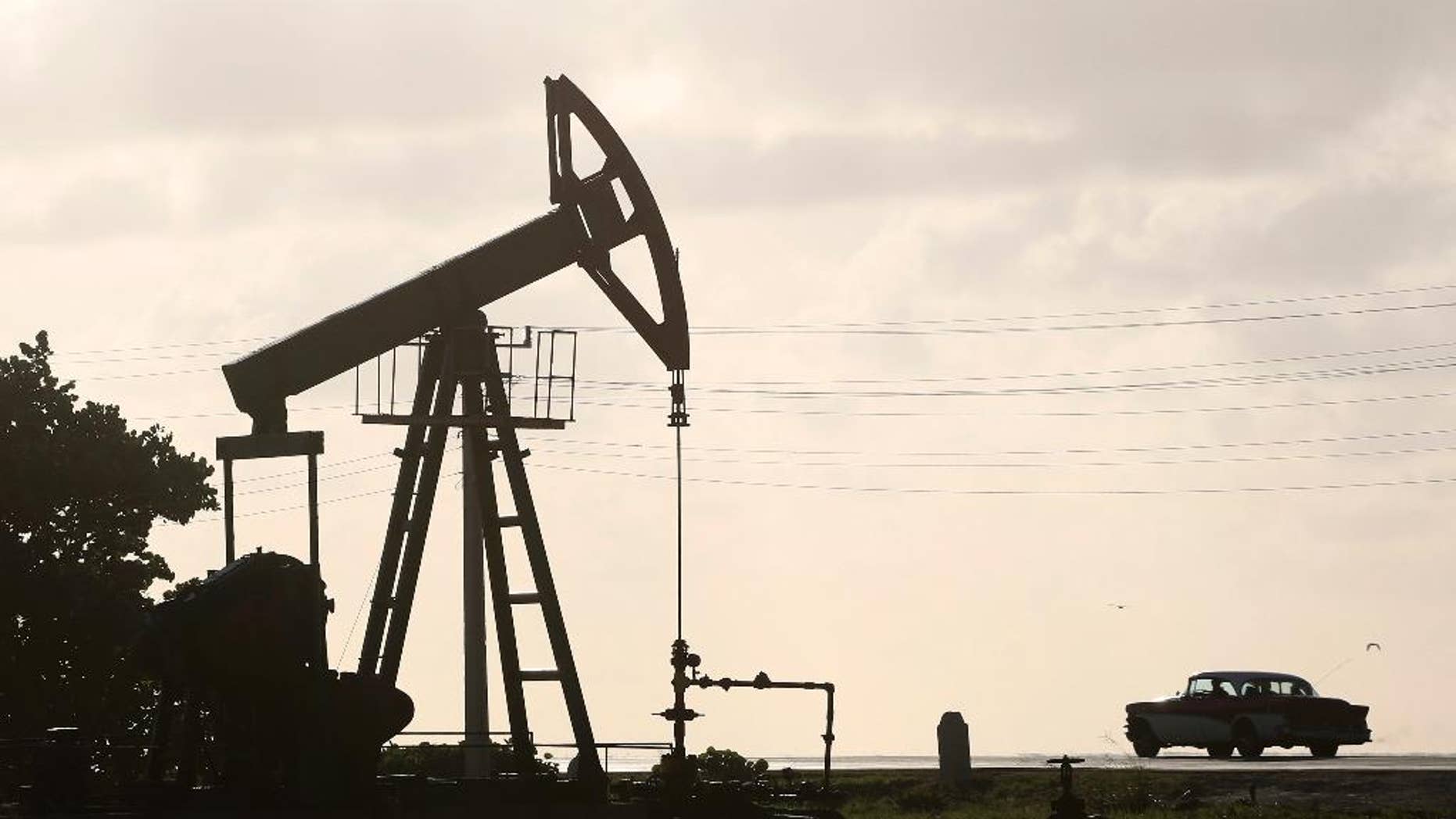 FILE - In this July 11, 2014 file photo, an oil well pump operates in Boca de Jaruco, Cuba. Officials are warning of tough times with authorities ordering energy-saving measures and some state entities reducing hours of operation. (AP Photo/Desmond Boylan, File)