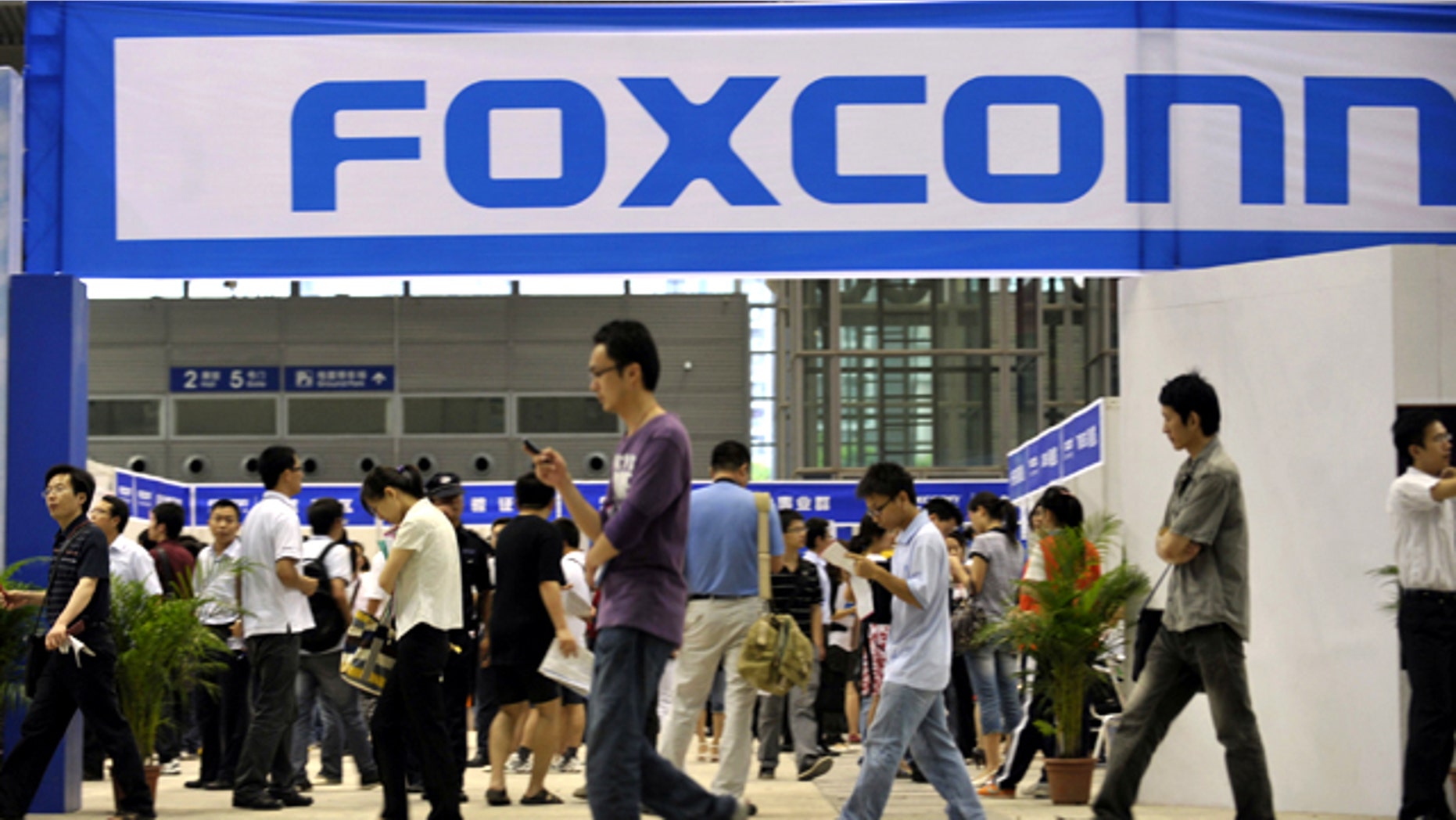 May 22, 2010: Visitors to a job fair walk past the Foxconn recruitment area in Shenzhen in south China's Guangdong province.