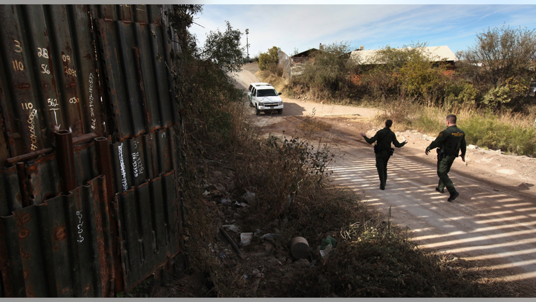 NOGALES, AZ - DECEMBER 07: U.S. Border Patrol agents Richard Funke (R) and Colleen Agle walk along a patched section of the border fence at the U.S.- Mexico border on December 7, 2010 near Nogales, Arizona. Although a new fence has been built along the majority of Arizona's border with Mexico, critics have called for fencing of the entire stretch. Much of the unfenced terrain is in remote and mountainous areas. (Photo by John Moore/Getty Images)