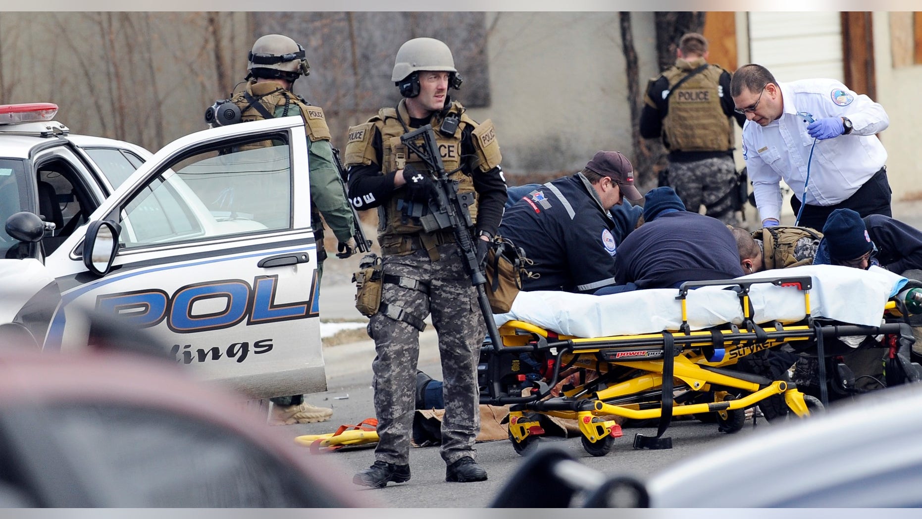 In this Sunday, Jan. 6, 2013 photo, SWAT team members stand guard as a man is given CPR after a standoff with police and the SWAT team in Billings, Mont. The standoff ended with the death of a handcuffed burglary suspect who hit a Montana police officer with his own patrol car before the officer opened fire. (AP Photo/The Billings Gazette, James Woodcock)