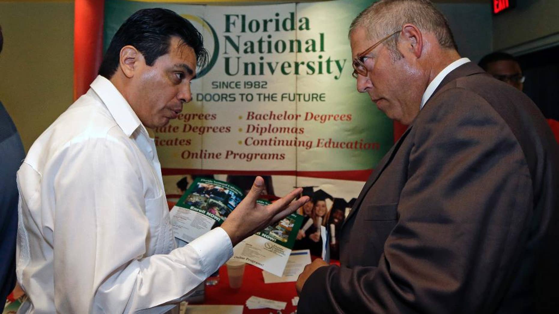 In this photo taken Wednesday, July 15, 2015, Luigi Valdivieso, left, talks about job opportunities to Richard Solano at a job fair in Miami Lakes, Fla. The Labor Department reports on state unemployment rates for June on Tuesday, July 21, 2015. (AP Photo/Alan Diaz)