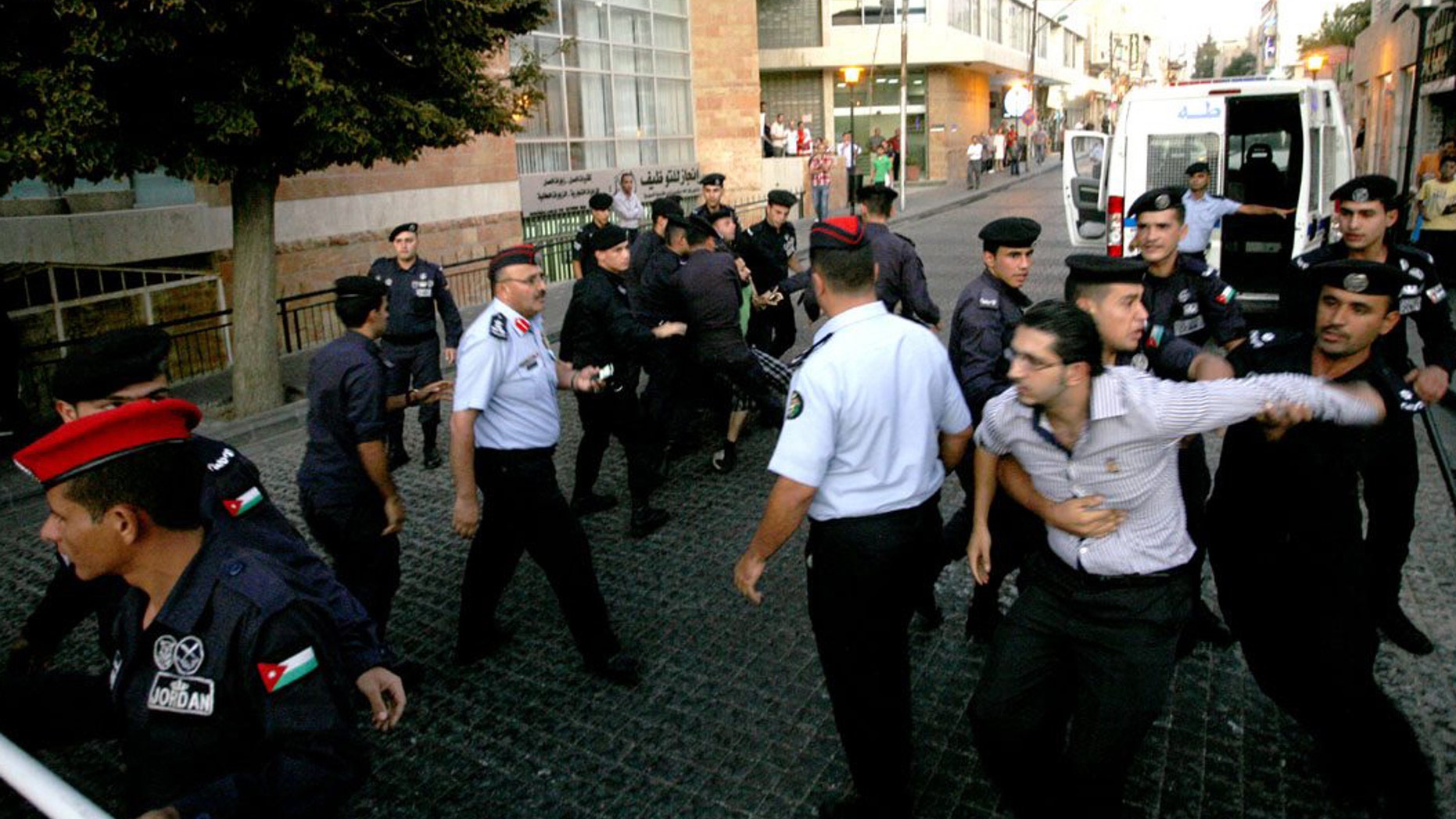 In this Monday, Sept. 11, 2011 photo, Jordanian security police officers arrest Khaled Natour, right, and Nihad Zuhair, background left, in front of the Saudi Arabia embassy, in Amman, Jordan. Jordan says it has no official word from Saudi Arabia about one of its citizens apprehended by authorities there 50 days ago. Jordanian foreign ministry spokeswoman Sabah Rafie told the Associated Press Monday that Jordan has yet to receive a formal response regarding the detention of Natour at Riyadh airport. (AP Photo/Mohammad Hannon)