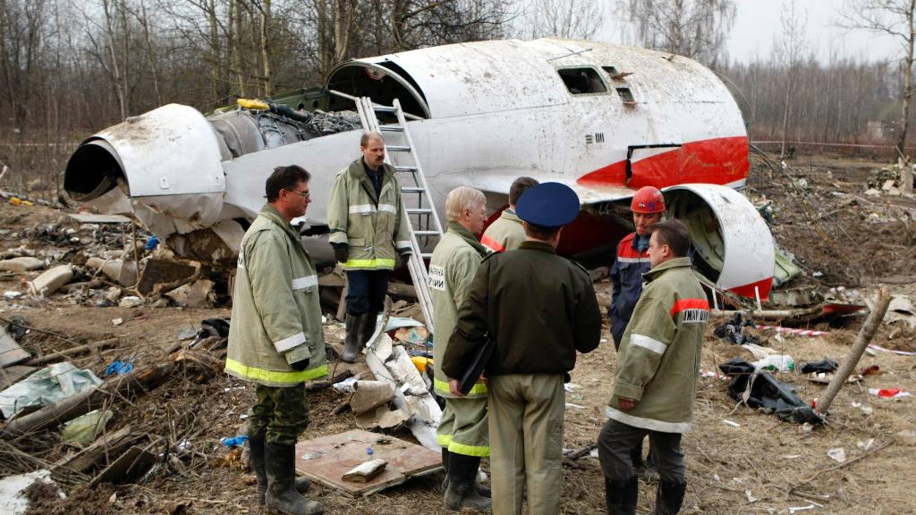 FILE - In this April 13, 2010 file photo, emergency ministry workers stand near the wreckage at the site of the plane crash that killed Polish President Lech Kaczynski in Smolensk, western Russia. Poland's government is accusing European Council President Donald Tusk of betraying national interests and bowing to Moscow in the investigation of the 2010 plane crash in Russia that killed Kaczynski and 95 others. (AP Photo/Mikhail Metzel, File)