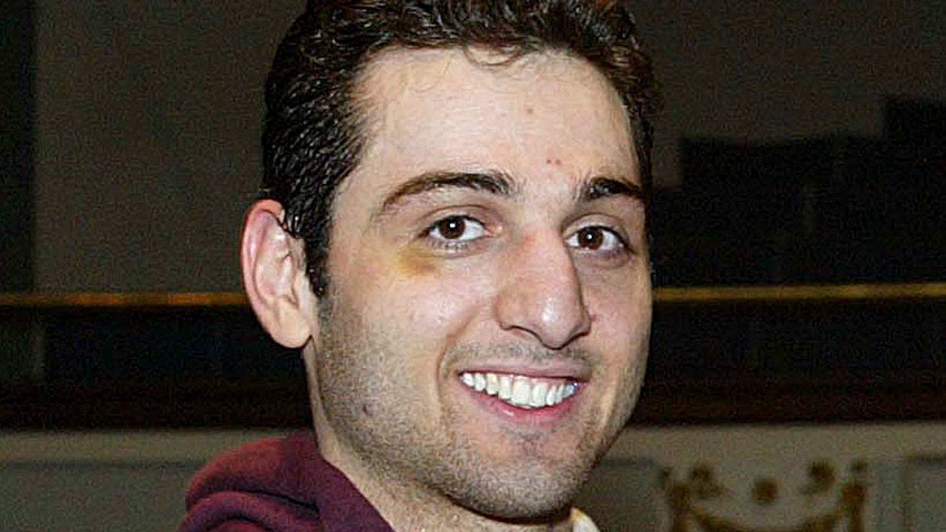FILE - In this Feb. 17, 2010, photo, Tamerlan Tsarnaev, left, smiles after accepting the trophy for winning the 2010 New England Golden Gloves Championship in Lowell, Mass. Tsarnaev, the older of the brothers suspected in the Boston Marathon bombing, died from gunshot wounds and blunt trauma to his head and torso, his death certificate says. (AP Photo/The Lowell Sun, Julia Malakie, File) MANDATORY CREDIT