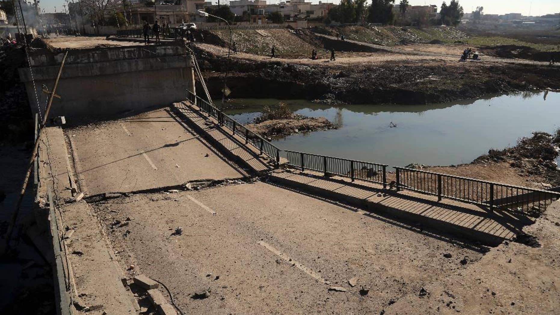 People inspect a bridge destroyed by Islamic State militants in a neighborhood recently liberated from Islamic State on the eastern side of Mosul, Iraq, Thursday, Jan. 12, 2017. Small stalls and carts have sprung up outside the bombed-out restaurants and cafes in eastern Mosul, selling fresh vegetables, cigarettes and cellphones to the thousands of civilians still living in neighborhoods where the Iraqi military has driven out the extremists of the Islamic State group.(AP Photo/ Khalid Mohammed)