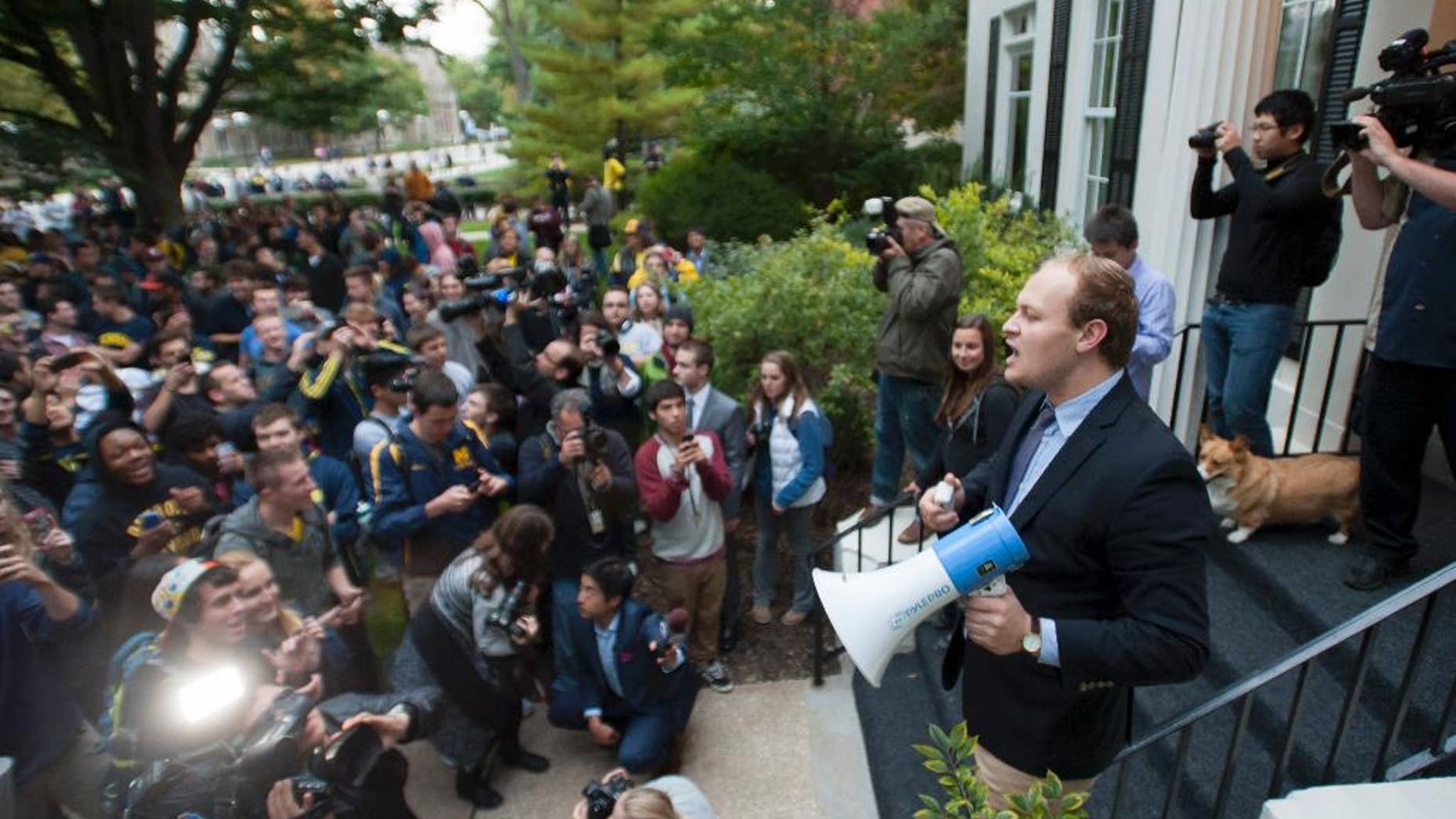 In a Sept. 30, 2014 photo, Craig Kaplan, a senior at the University of Michigan, uses a bullhorn to rally the protestors who gathered outside the residence of University of Michigan President Mark Schlissel at the University of Michigan over the recent football game where quarterback Shane Morris was left in the game after receiving a concussion. About 1,000 University of Michigan students marched to the home of Schlissel to protest against the performance of athletic director Dave Brandon and football coach Brady Hoke. (AP Photo/The Detroit News, David Guralnick)