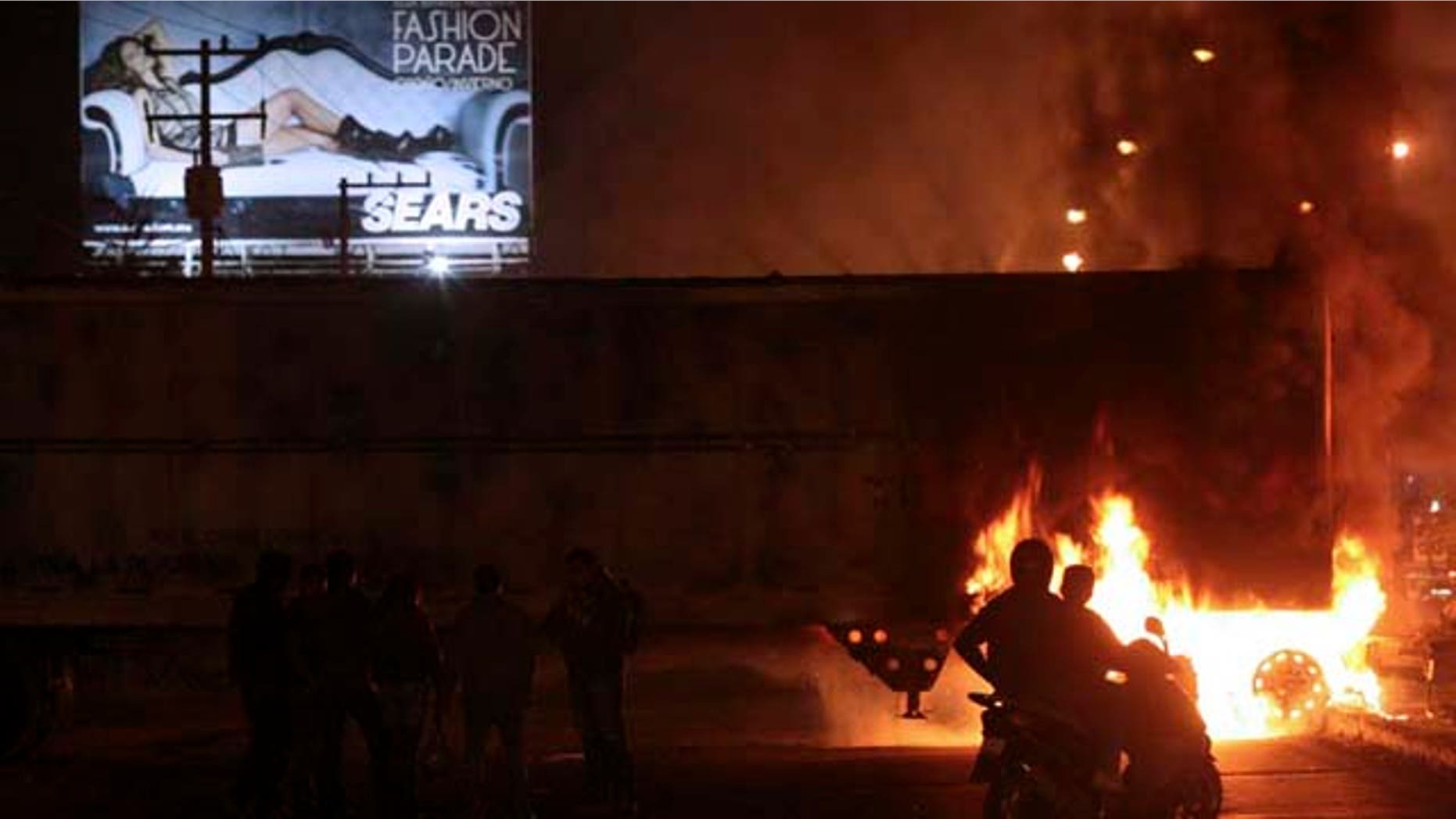 People watch as a truck blocking the road burns Mexico. Friday Nov. 5, 2010.
