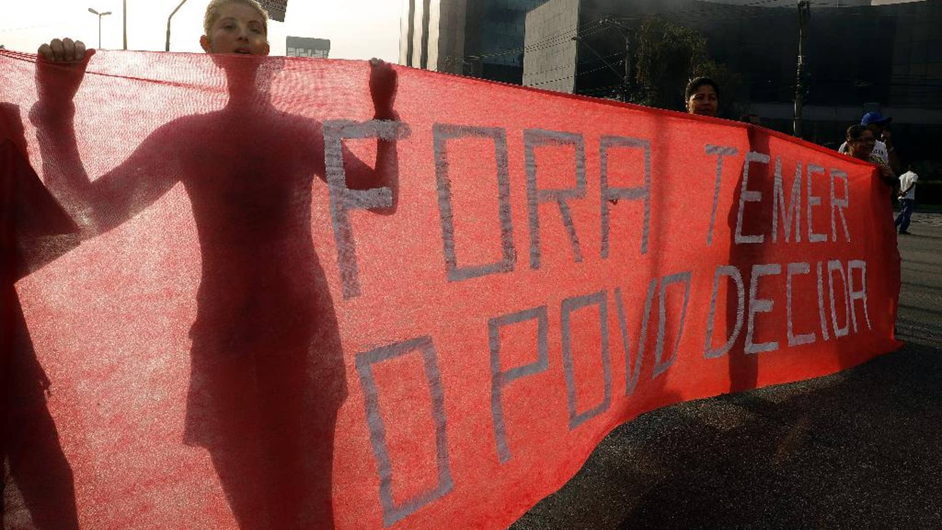 Demonstrators hold a banner that reads in Portuguese; "Temer out, the people decide" during a protest against Brazil's acting President Michel Temer, in Sao Paulo, Brazil, Tuesday, Aug. 30, 2016. Suspended President Dilma Rousseff mounted a forceful defense at her impeachment trial Monday, blasting her critics ahead of a Senate vote that could come Tuesday on whether to remove her from office permanently. (AP Photo/Andre Penner)