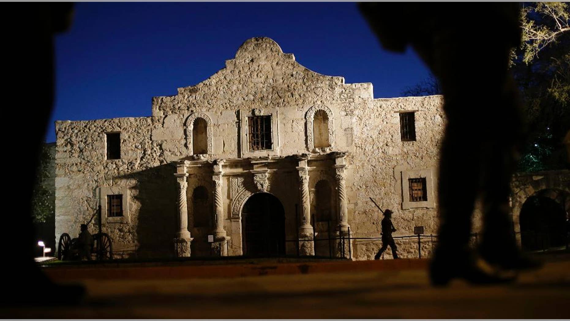 FILE - In this March 6, 2013, file photo, Dan Phillips, a member of the San Antonio Living History Association, patrols the Alamo during a pre-dawn memorial ceremony to remember the 1836 Battle of the Alamo and those who fell on both sides, in San Antonio. The Daughters of the Republic of Texas, a group that served as guardian of the Alamo for more than a century and the Texas General Land Office, reached a settlement Friday, June 24, 2016, in a dispute over ownership of about 38,000 books and artifacts that had been kept at the Texas shrine. (AP Photo/Eric Gay, File)