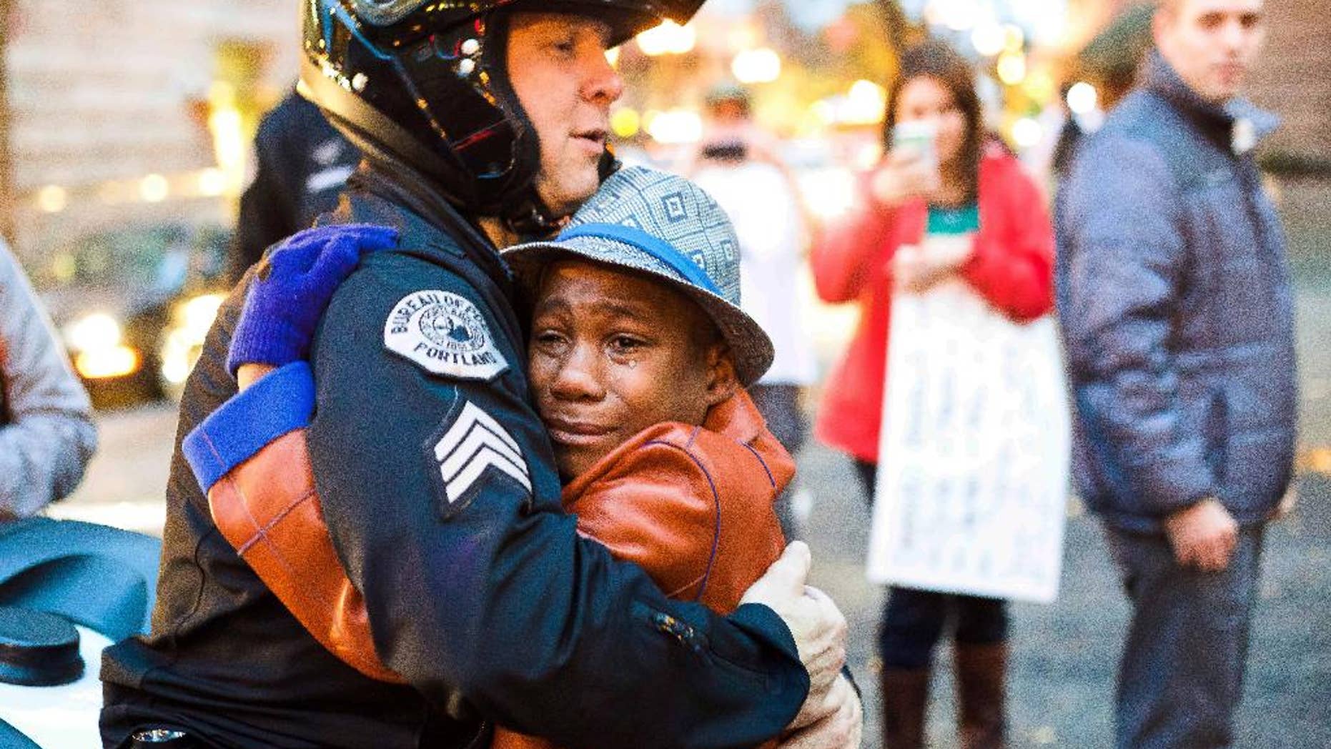 In this Tuesday, Nov. 25, 2014 photo provided by Johnny Nguyen, Portland police Sgt. Bret Barnum, left, and Devonte Hart, 12, hug at a rally in Portland, Ore., where people had gathered in support of the protests in Ferguson, Mo. (AP Photo/Johnny Huu Nguyen)