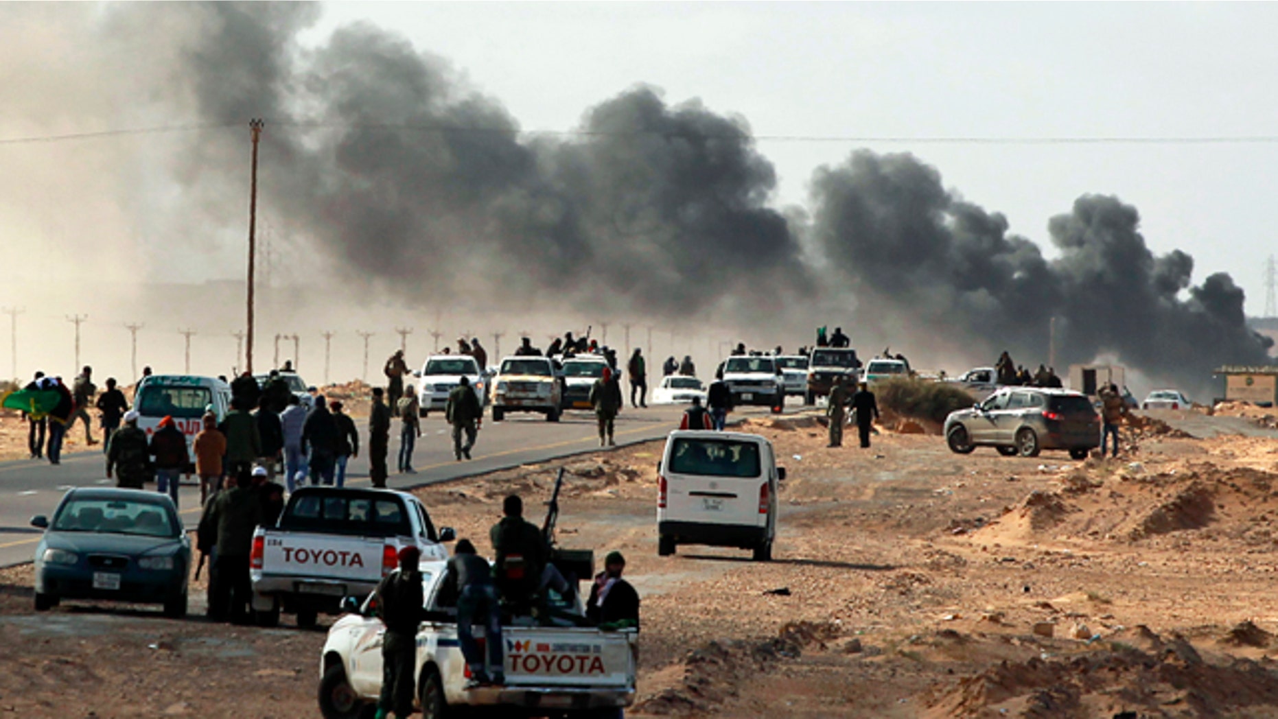 Smoke rises from heavy shelling as Libyan rebels who are part of the forces against Libyan leader Moammar Gadhafi retreat during a battle with Gadhafi's troops, outside the town of Bin Jawwad, eastern Libya, Sunday, March 6, 2011