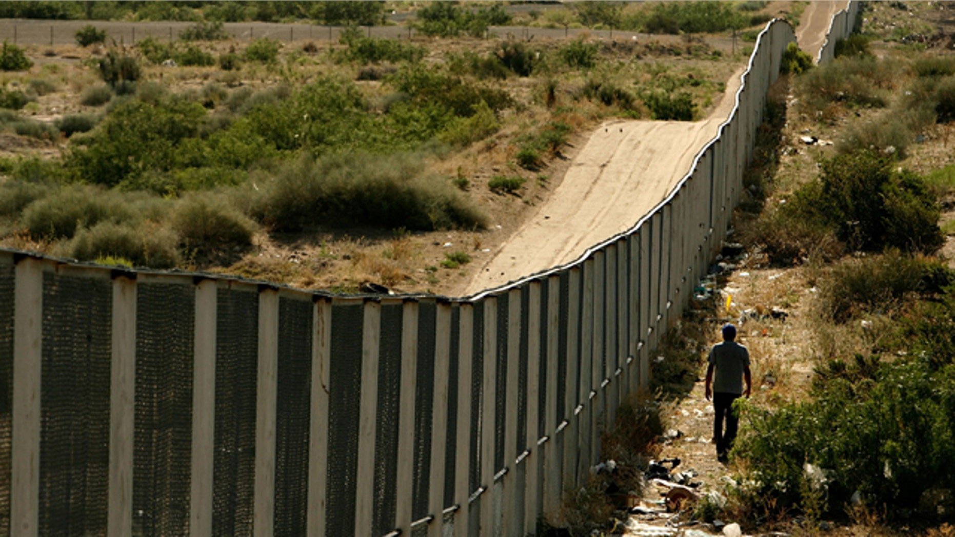 CIUDAD JUAREZ, CHIHUAHUA - JUNE 29: A man walks along the border fence between the U.S. and Mexico on June 29, 2007 in the Anapra area of Ciudad Juarez, Mexico. This area is a popular crossing spot for immigrants to ilegally cross into the United States because houses are close to the border on the south side and the highway is close to the north side. (Photo by Chip Somodevilla/Getty Images)