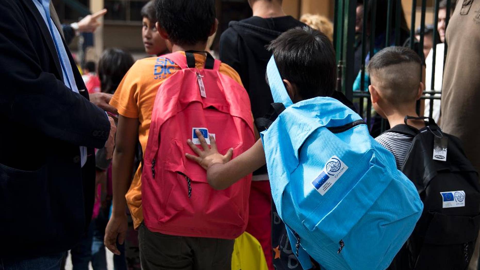 Refugee children enter a primary school in Athens during the first day of lessons under the new refugee schooling program, on Monday, Oct. 10, 2016. More than 60,000 refugees are stranded in Greece due to European border closure. (AP Photo/Petros Giannakouris)