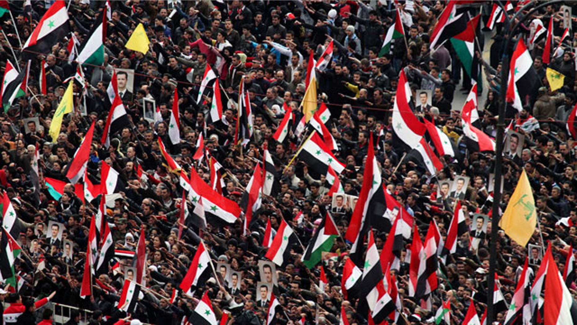 Jan. 11, 2012: Pro-Syrian regime protesters wave the national flag, as well as Hezbollah flags, in yellow, as they gather during a demonstration to show support for Syrian President Bashar Assad at a central square in Damascus, Syria.