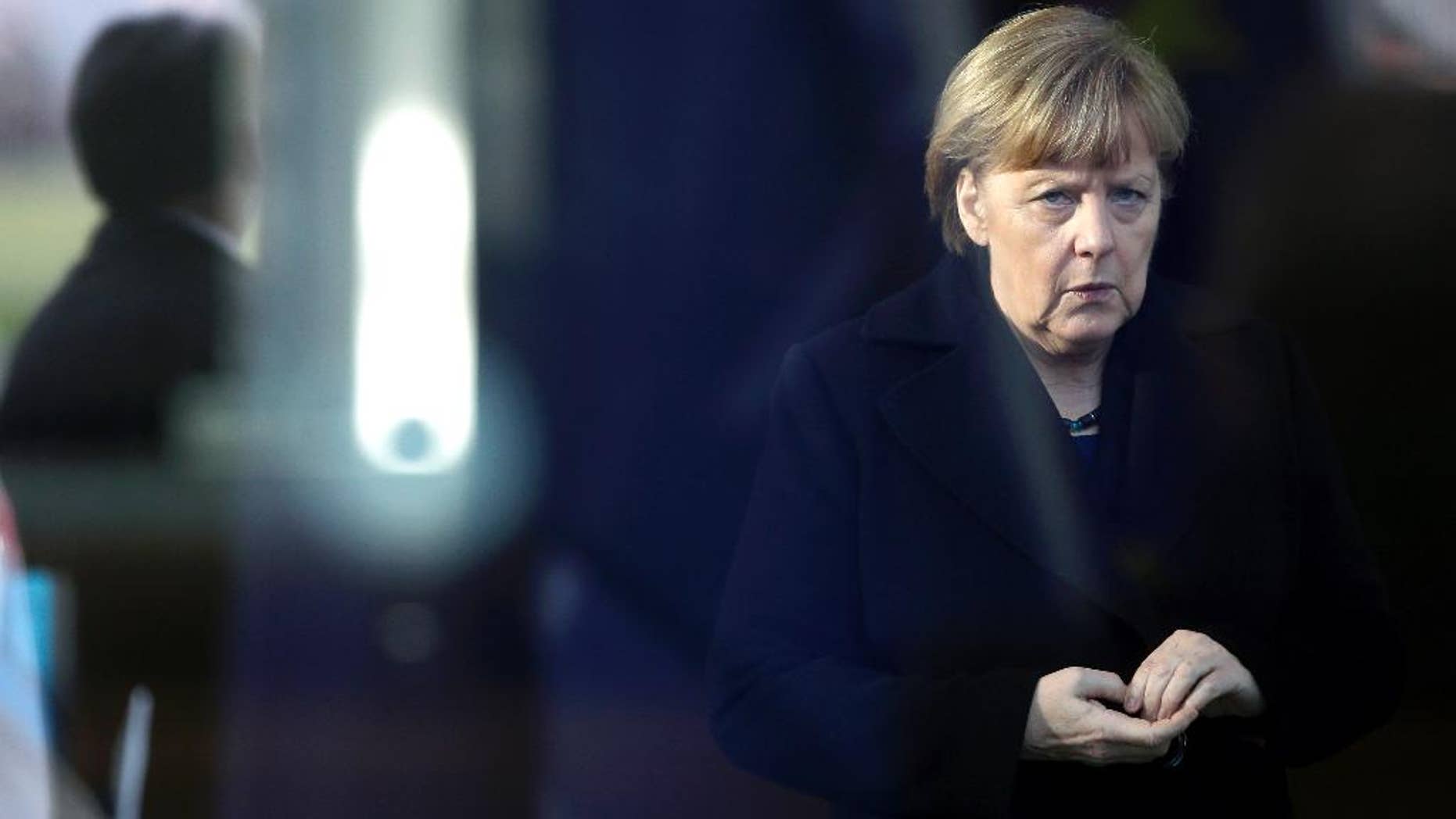 German Chancellor Angela Merkel is pictured trough a window as she waits for the arrival of NATO Secretary General Jens Stoltenberg at the chancellery in Berlin, Germany, Wednesday, Jan. 14, 2015. (AP Photo/Michael Sohn)