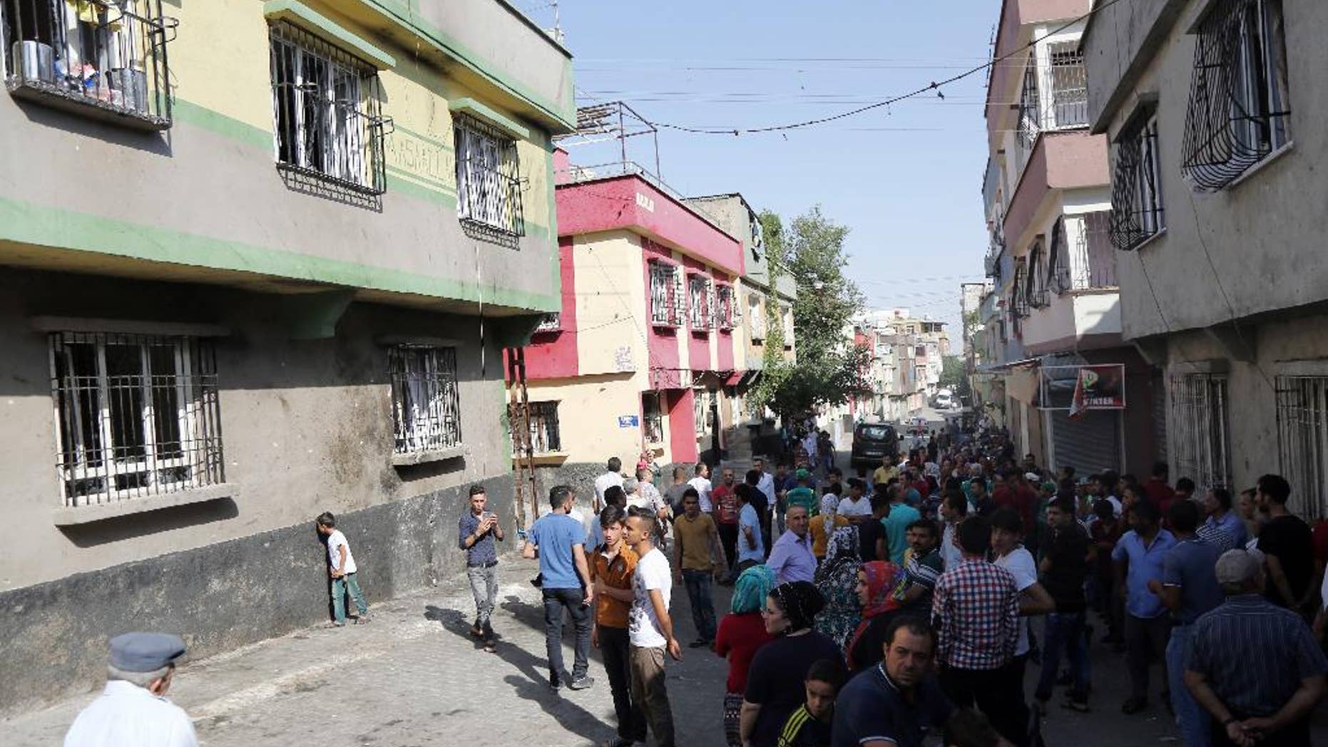 People gather near to the scene of Saturday's bomb attack targeting an outdoor wedding party that killed dozens in Gaziantep, southeastern Turkey, Sunday, Aug. 21, 2016. Deputy Prime Minister Mehmet Simsek said the "barbaric" attack in Gaziantep, near the border with Syria, on Saturday appeared to be a suicide bombing. Turkish authorities have put a temporary ban on distribution of images relating to Saturday's Gaziantep attack within Turkey. (AP Photo/Mahmut Bozarslan)