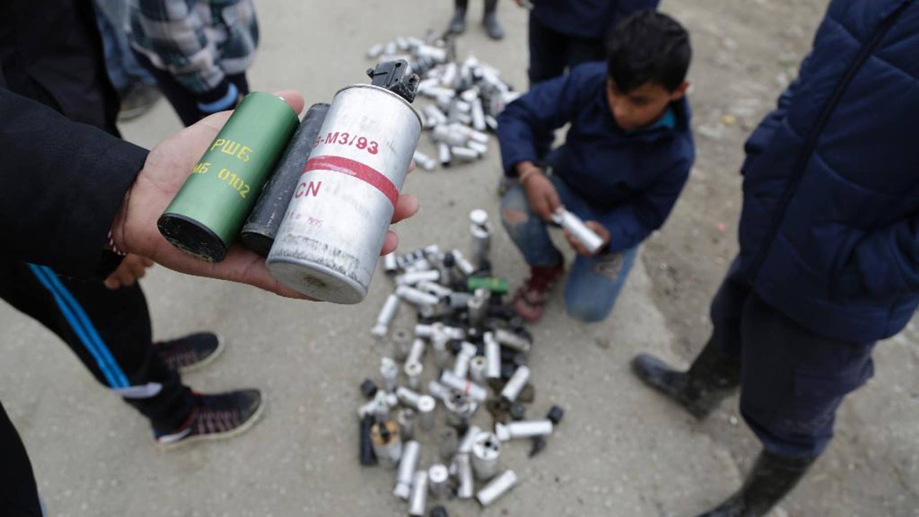 Migrant men shows used tear gas canisters apparently used by Macedonian police during yesterday riots at the fence of a makeshift camp in the northern Greek border point of Idomeni, Greece, Monday, April 11, 2016. More than 12,000 people have been stuck at the Idomeni border point for more than a month hoping that it would reopen. (AP Photo/Amel Emric)