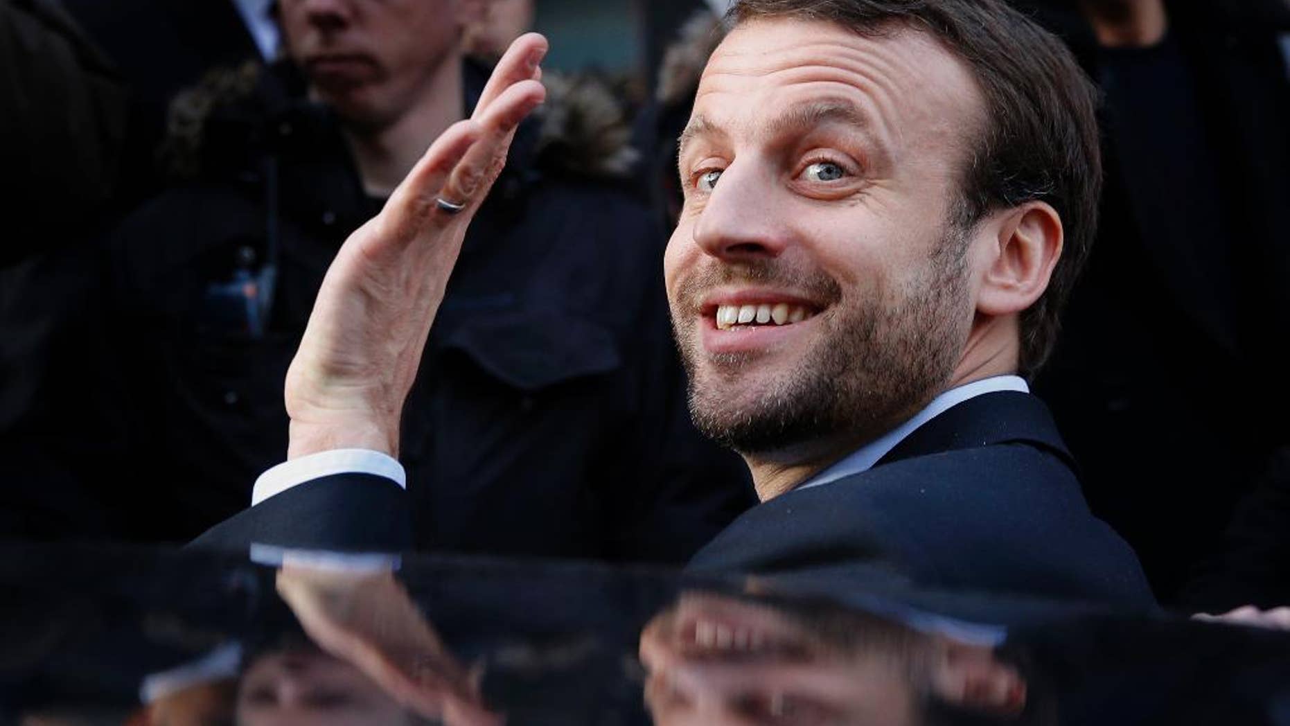 FILE - In this Jan.6, 2016 file photo, French Economy Minister Emmanuel Macron waves as he leaves after a visit to a shopping center in Paris, France. France's presidential candidate Emmanuel Macron pledges for re-opening discussions with Russia and make from the fight against the Islamic State group a priority. (AP Photo/Christophe Ena, File)