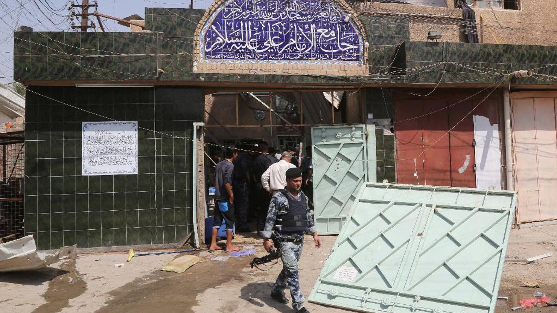 Security forces and civilians inspect the damage outside Imam Ali mosque in New Baghdad, Iraq, Monday, Aug. 25, 2014. Iraqi officials say a wave of attacks targeting commercial areas in and outside Baghdad has killed and wounding scores of people. They say the deadliest of Monday's bombings was carried out by a suicide bomber who blew up himself among Shiite worshippers who were leaving Imam Ali mosque after noon prayers in the capital's eastern New Baghdad area, killing at least 15 people and wounding 32 others.(AP Photo/ Khalid Mohammed)