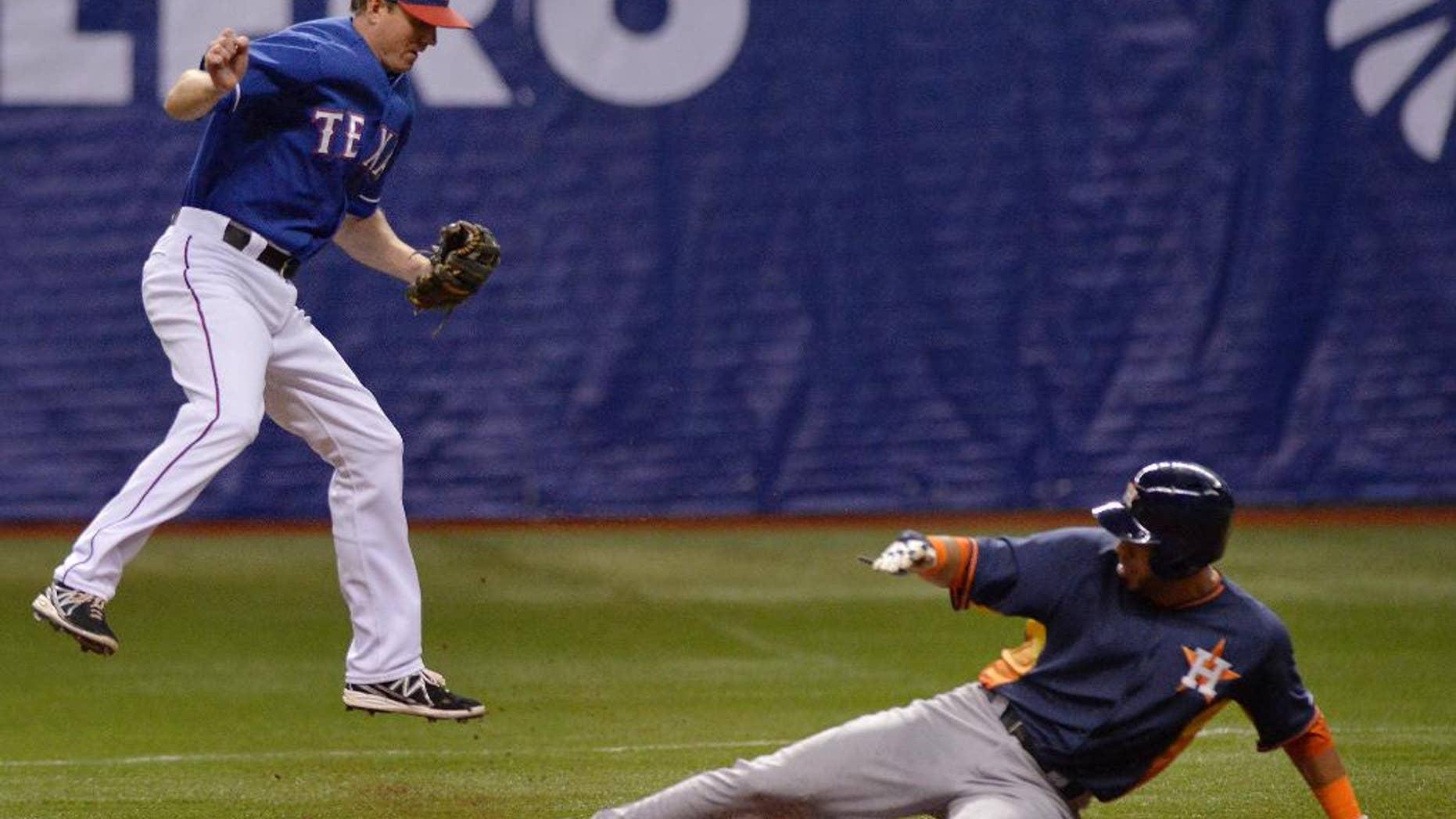 Texas Rangers' Josh Wilson, left, leaps to catch the ball as Houston Astros' Marwin Gonzalez slides safely into second base during a spring exhibition baseball game on Saturday, March 29, 2014, in San Antonio. (AP Photo/Darren Abate)