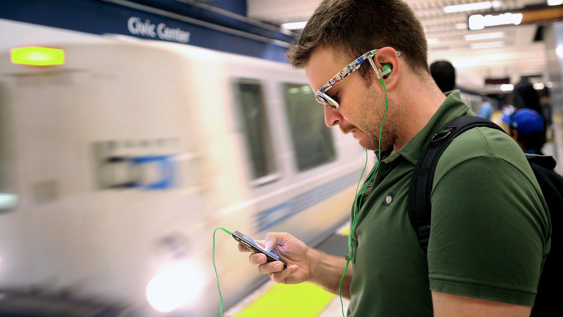 FILE: Aug. 13, 2011: A man checks his cell phone while waiting for a BART train at San Francisco's Civic Center station, in Calif.