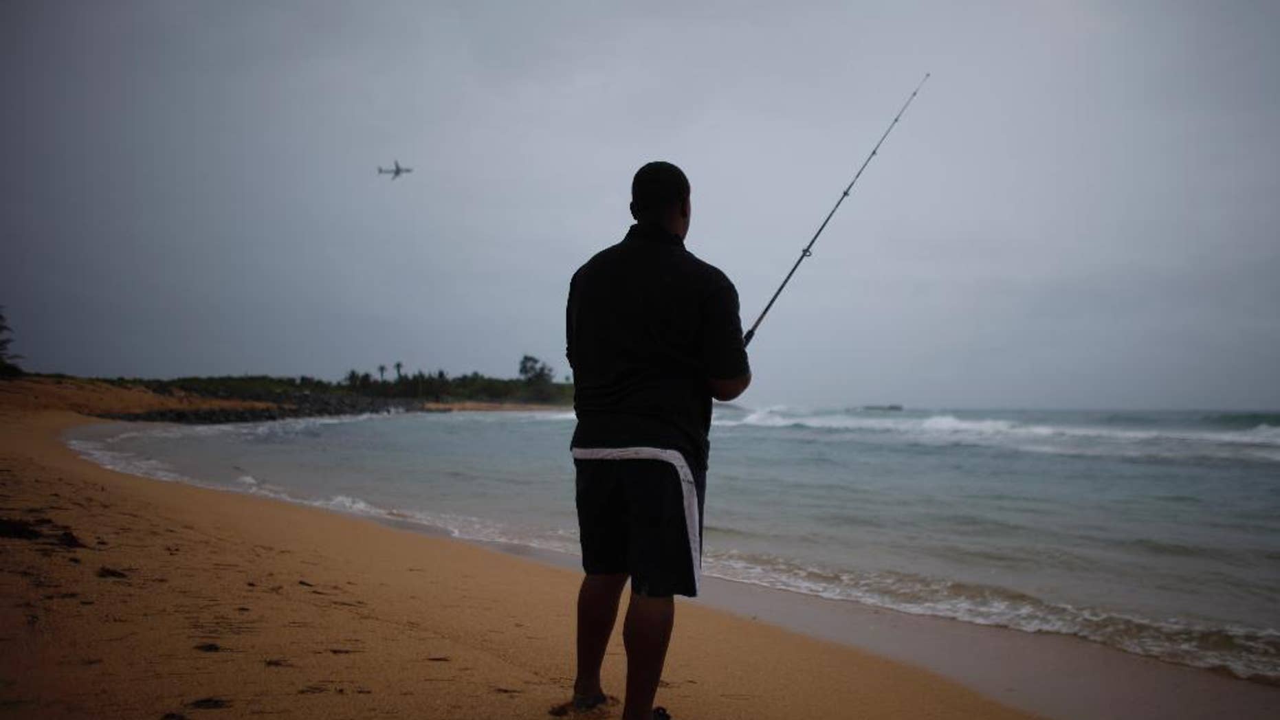 A man fishes as a cluster of storms passes through the area, in San Juan, Puerto Rico, Friday, Aug. 22, 2014. The National Weather Service in San Juan said the region could be hit with up to 6 inches (15 centimeters) of rain and wind gusts of 35 mph (56 kph). (AP Photo/Ricardo Arduengo)