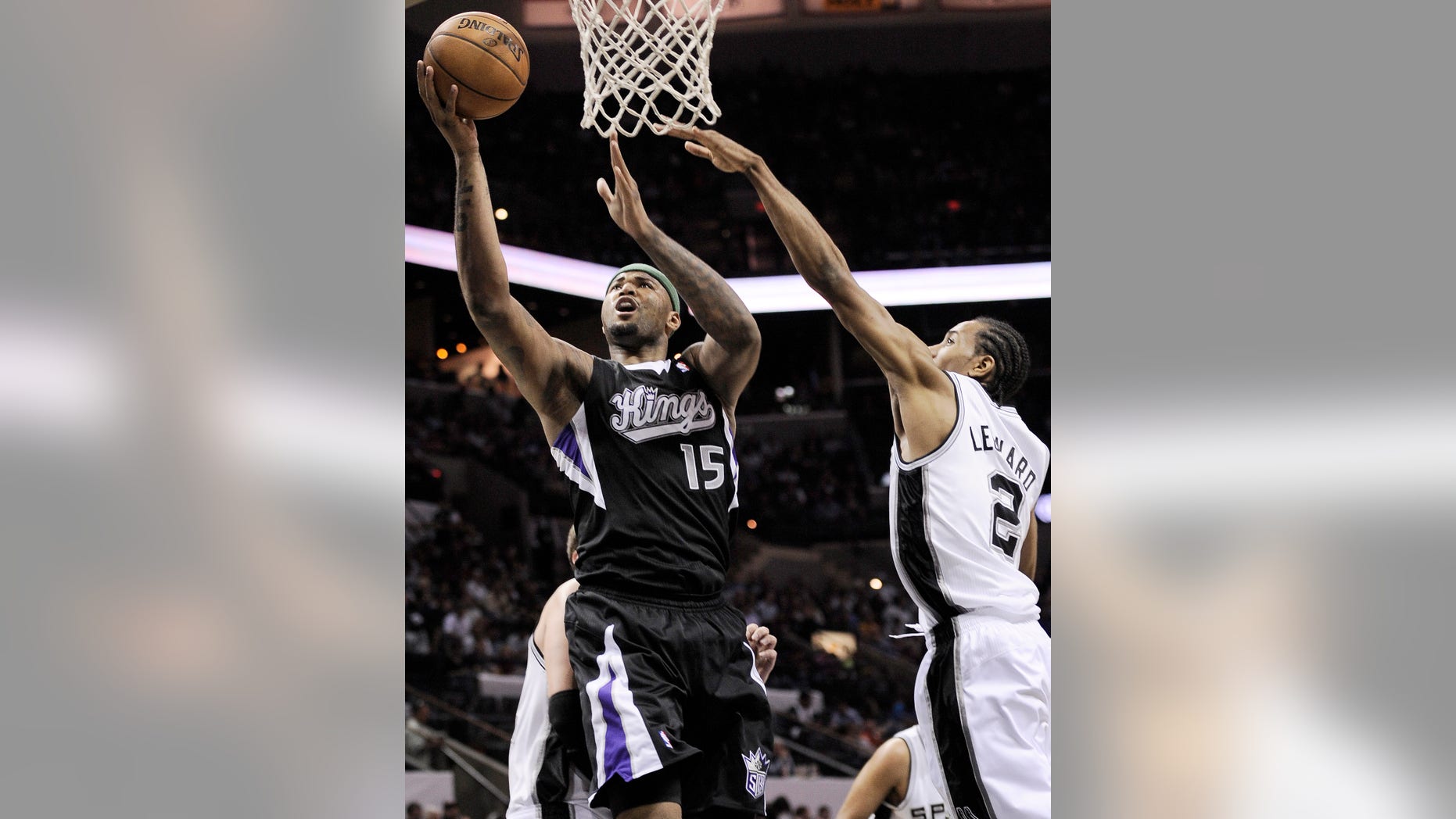 Sacramento Kings' DeMarcus Cousins, left, shoots against San Antonio Spurs' Kawhi Leonard during the second half of an NBA basketball game, Friday, April 12, 2013, in San Antonio. San Antonio won 108-101. (AP Photo/Darren Abate)