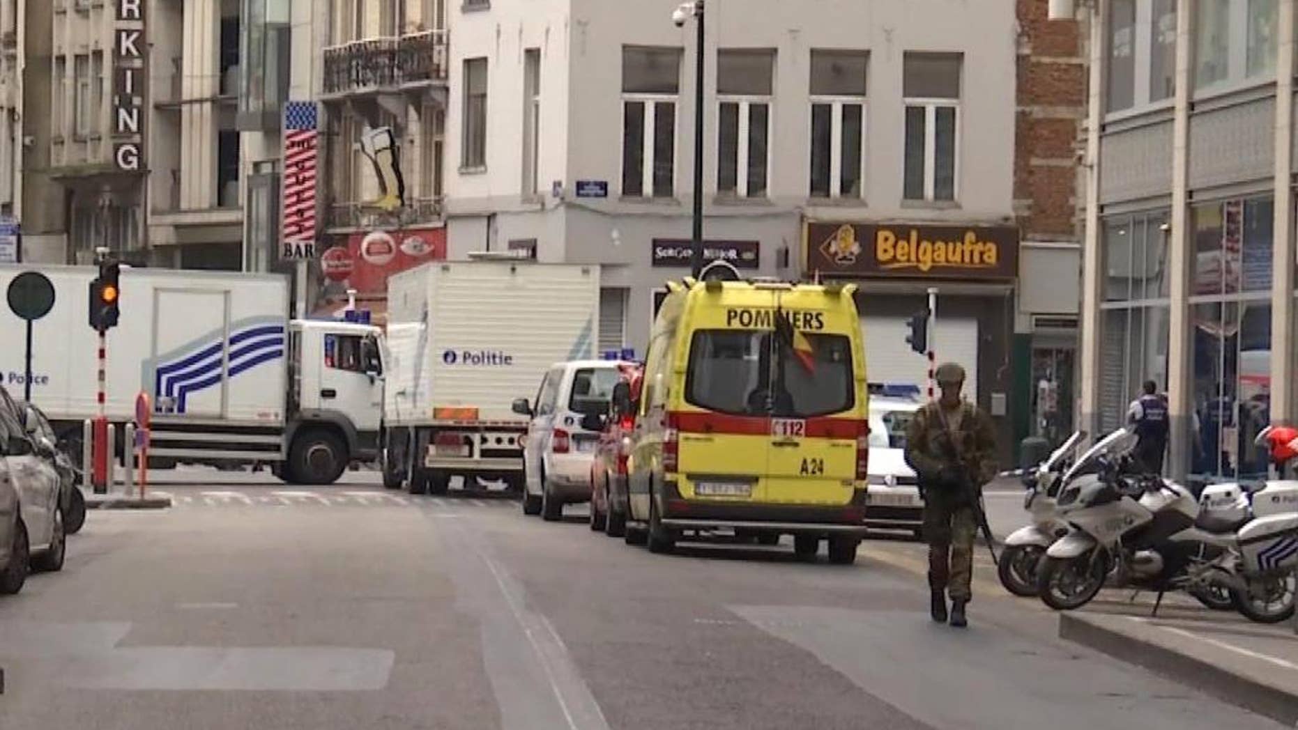 In this framegrab taken from APTN, a soldier walks along a street in Brussels, Belgium, Wednesday July 20, 2016. Police in Brussels say they arrested a man acting suspiciously and wearing heavy clothes with wires hanging out, in the area of place Monnaie. Police closed the area and evacuated people surrounding the area. (AP Photo/APTN)