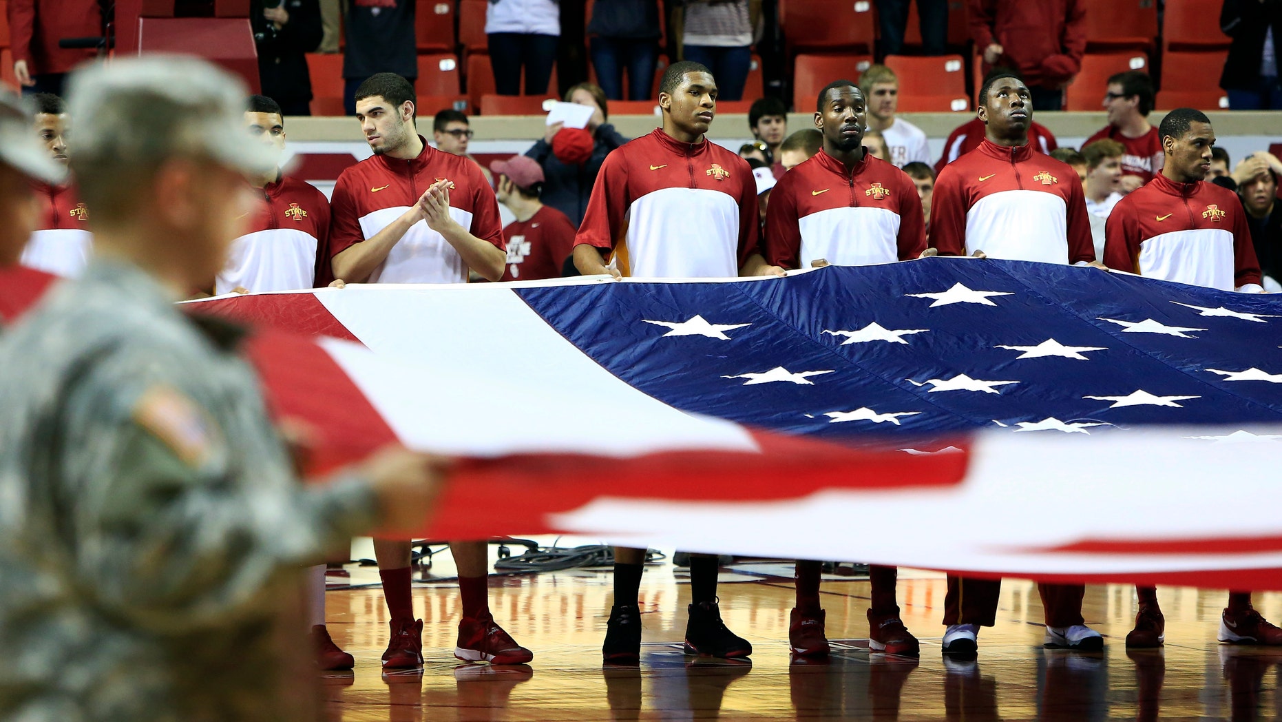 Iowa State members help hold the American flag before the start of an NCAA college basketball game against Oklahoma in Norman, Okla. on Saturday, Jan. 11, 2014. (AP Photo/Alonzo Adams)