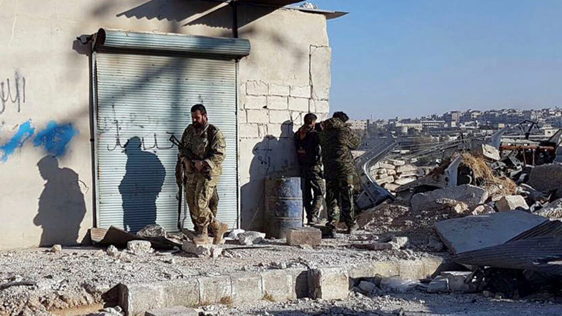 This Sunday, Nov. 27, 2016 photo provided by the Rumaf, a Syrian Kurdish activist group, which has been authenticated based on its contents and other AP reporting, shows Kurdish fighters watch people flee from rebel-held eastern neighborhoods of Aleppo into the Sheikh Maqsoud area that is controlled by Kurdish fighters, Syria. Syrian state media is reporting that government forces have captured the eastern Aleppo neighborhood of Sakhour, putting much of the northern part of Aleppo's besieged rebel-held areas under state control. (The Rumaf via AP)