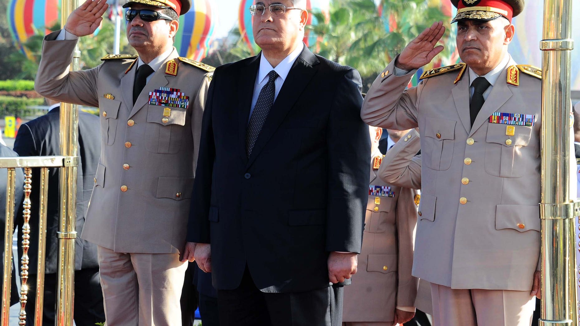 In this photo released by the Egyptian Presidency, Egypt's interim President Adly Mansour, center, Defense Minister Abdel-Fatah el-Sissi, left, and other officials visit the Tomb of the Unknown Soldier and President Anwar Sadat's memorial as part of celebrations marking the 40th anniversary of the start of the 1973 Middle East war in which Egyptian forces made initial gains against Israel, Saturday, Oct. 5, 2013. Egypt's army is on high alert ahead of expected mass demonstrations by supporters of ousted Islamist President Mohammed Morsi timed to coincide with annual celebrations honoring the military, a combination many fear will lead to a new round of violence. (AP Photo/Egyptian Presidency)