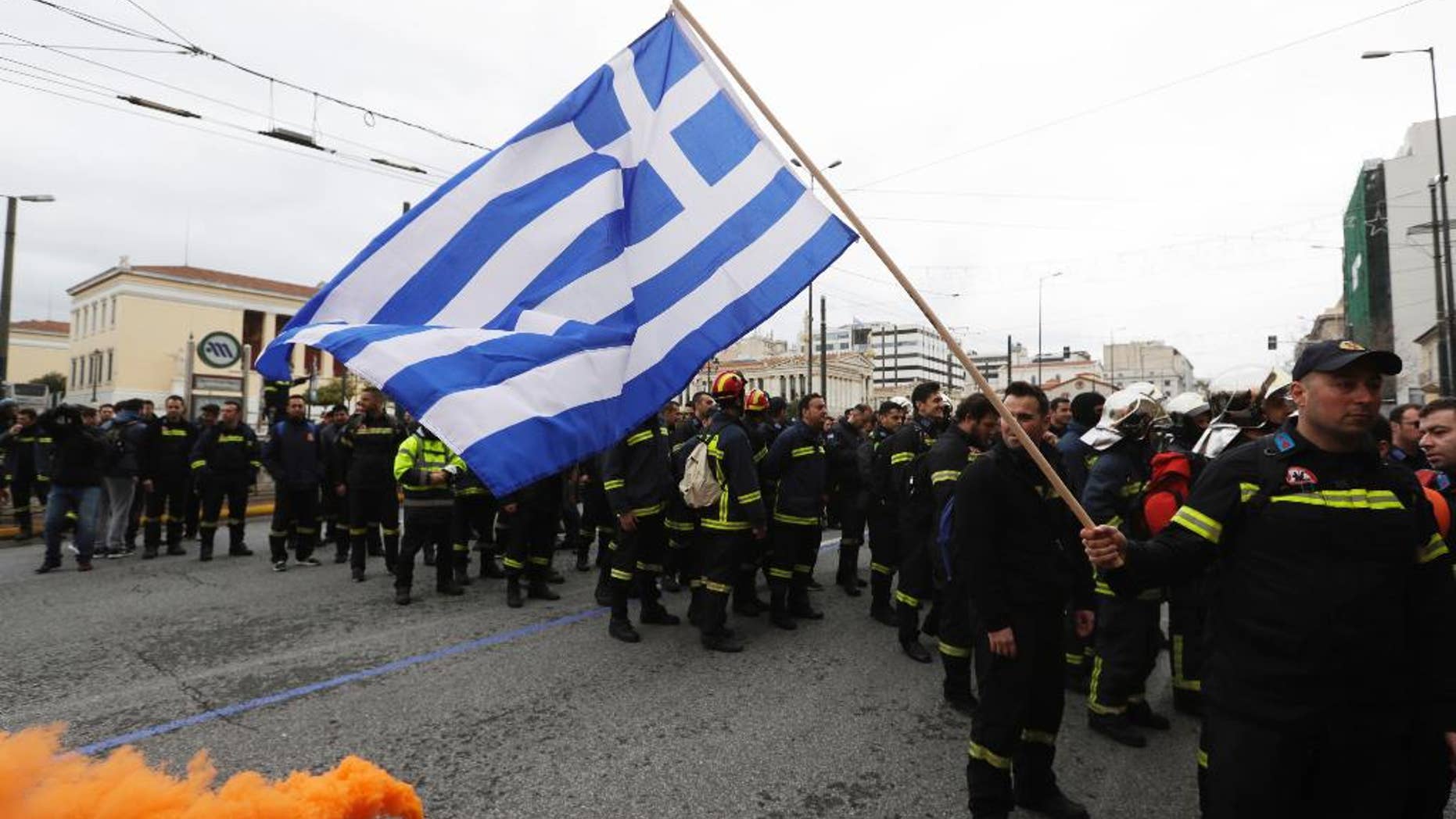 A firefighter holds a Greek flag during a protest in central Athens, on Wednesday, Feb. 8, 2017. Hundreds of firefighters in uniform have taken to the streets of the Greek capital to protest hiring conditions. (AP Photo/Thanassis Stavrakis)