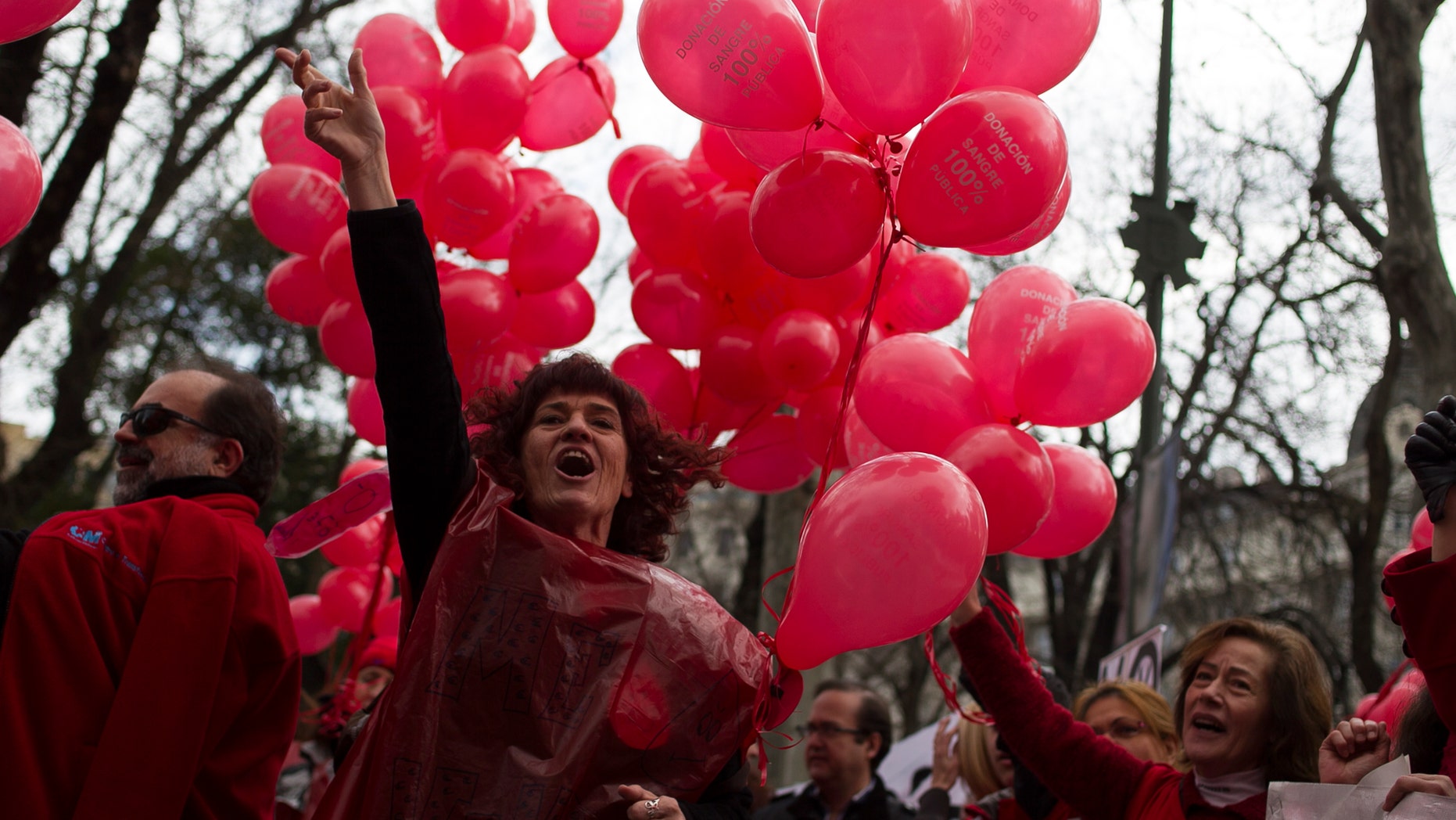 A protestor shouts slogans as she carries red balloons during a demonstration against the Madrid's regional government plans to privatize the blood donation centers, in Madrid, Spain, Sunday, Feb. 16, 2014. (AP Photo/Gabriel Pecot)