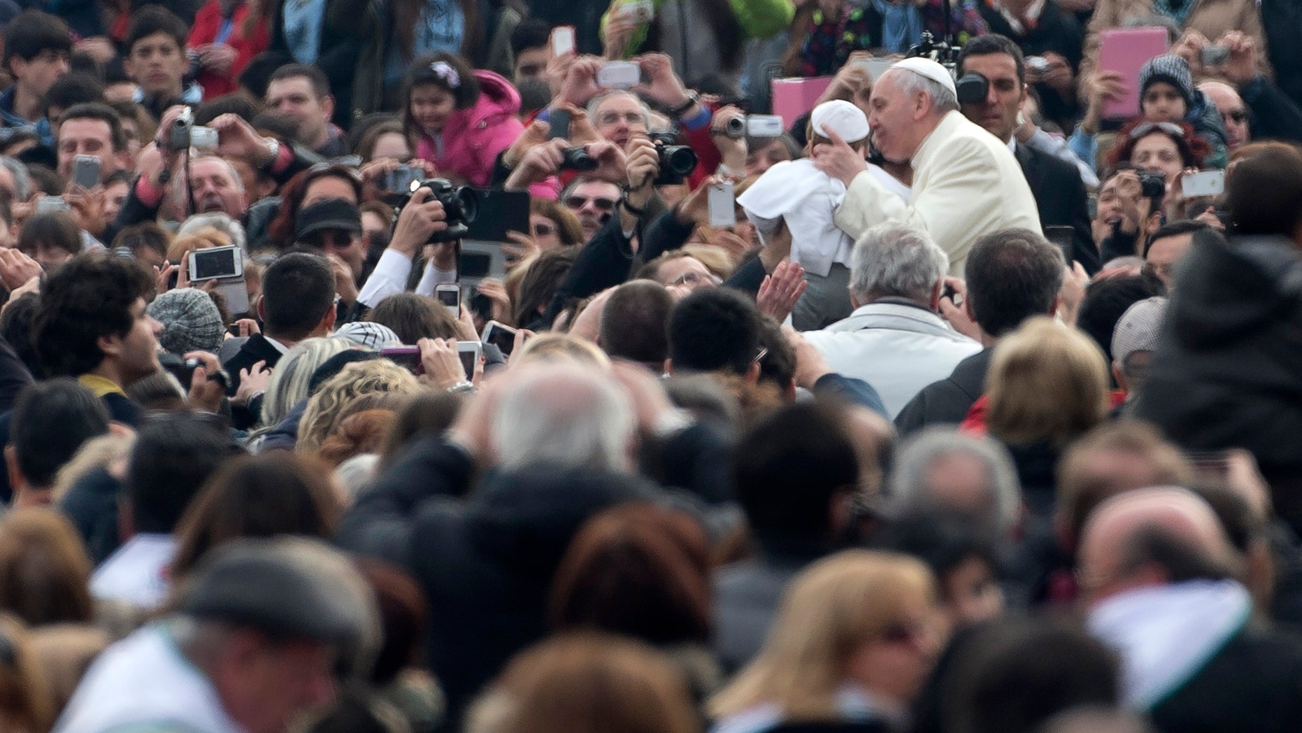 Pope Francis kisses a child named Daniele, last name not available, dressed as a Pope, as he arrives for his weekly general audience in St. Peter's Square at the Vatican, Wednesday, Feb. 26, 2014. The child, who was crying, was hoisted up to Francis as he drove by in his open-topped jeep. Another child dressed in a similar white cassock and white skullcap was also on hand as were kids dressed as Swiss Guards. During Carnival in Italy, children often go to school and spend their weekends dressed up in pirate, princess — and now pope — costumes. Carnival, also known as mardi gras, marks the period before the church's solemn Lenten season begins. (AP Photo/Alessandra Tarantino)