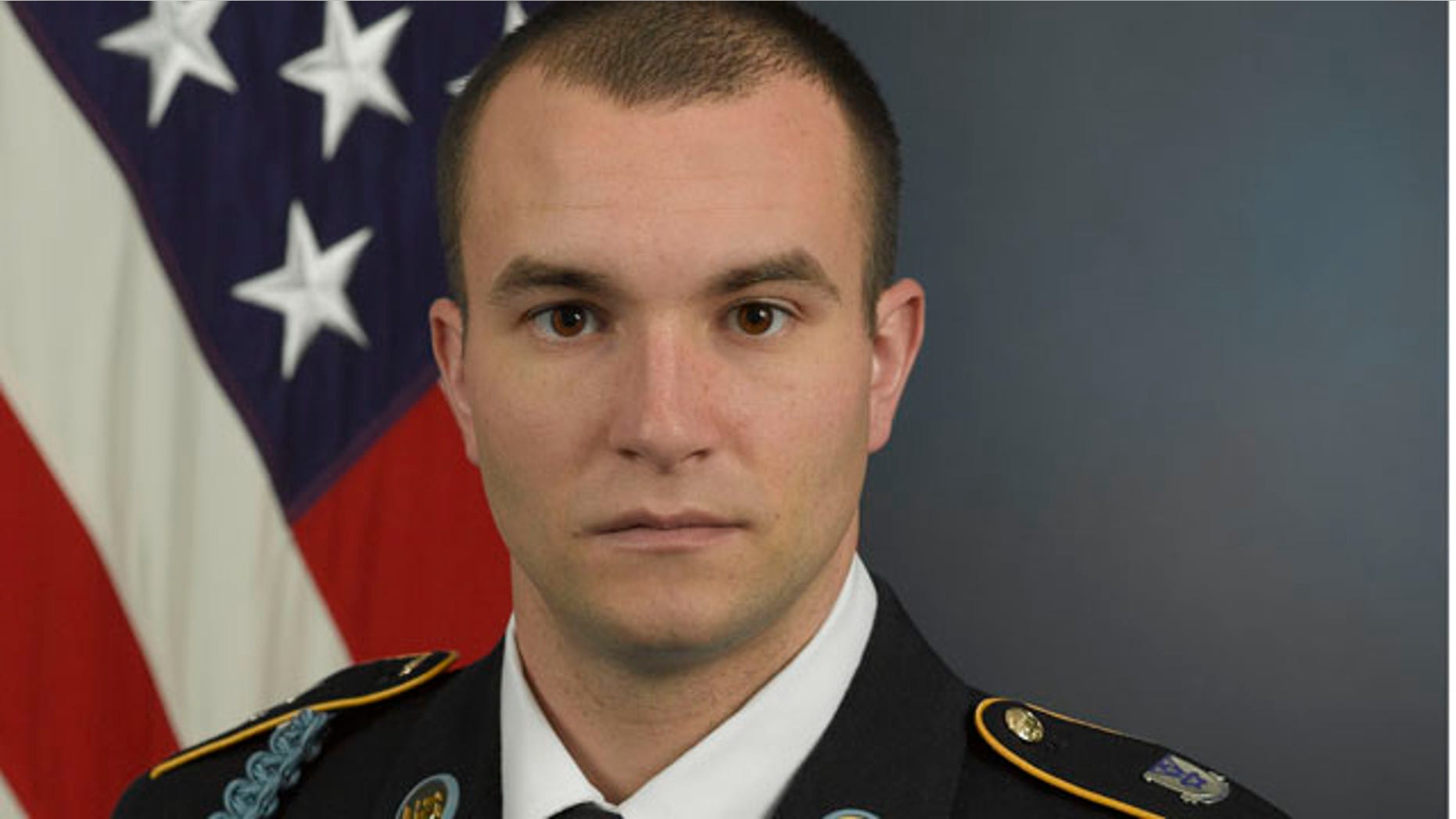 Staff Sgt. Salvatore Giunta poses in front of an American flag with his military uniform.