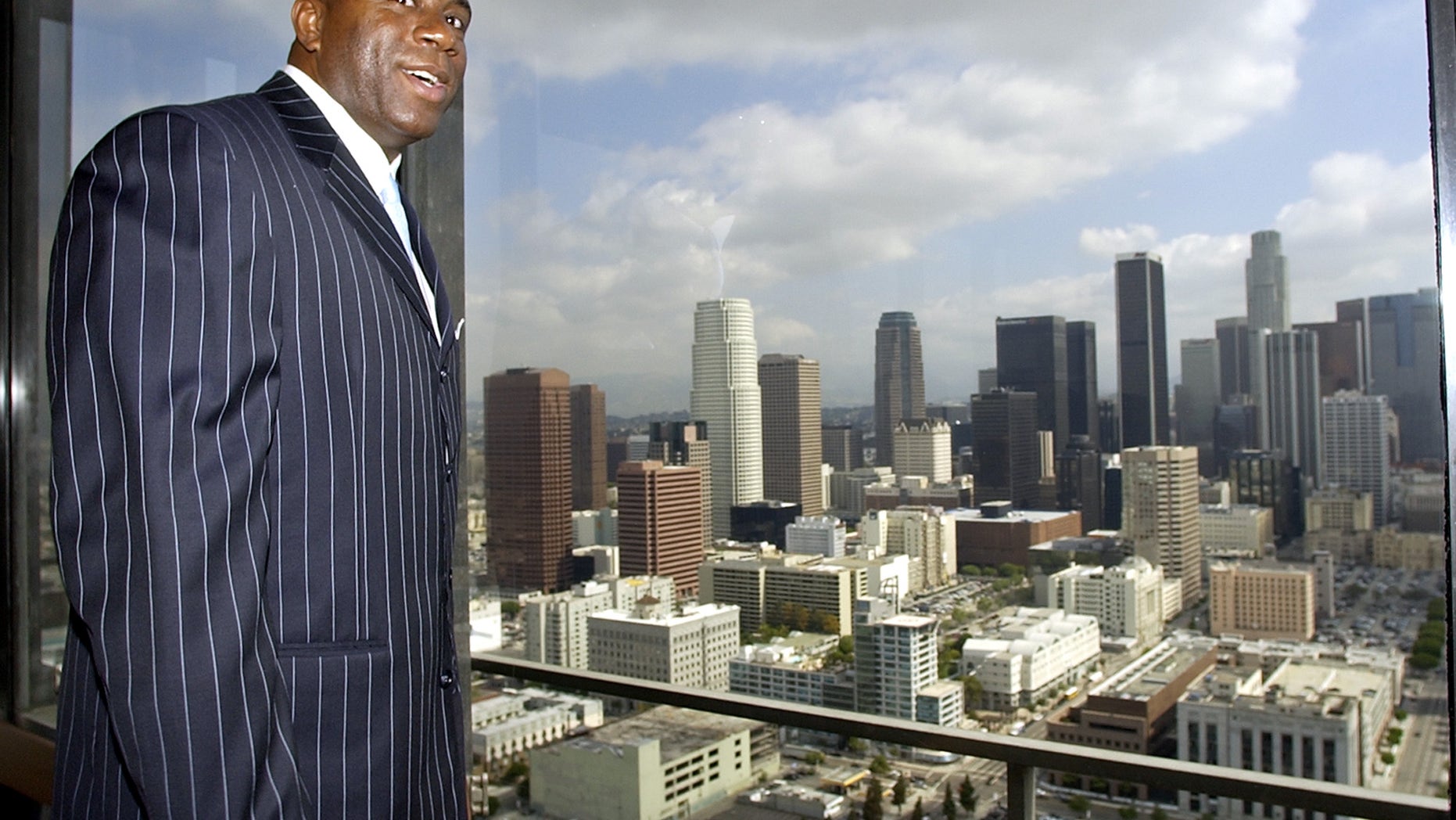 FILE - This April 23, 2003 file photo shows former Lakers star Magic Johnson showing the view of downtown Los Angeles from the top floor of the 32-story Transamerica Center, in Los Angeles. A person familiar with the situation says Magic Johnson is part of a group buying the Los Angeles Sparks of the WNBA. The person spoke to The Associated Press on condition of anonymity because no official announcement has been made. The WNBA will officially announce the new ownership at a press conference on Wednesday Feb. 5, 2014 outside the Staples Center. (AP Photo/Nick Ut, File)